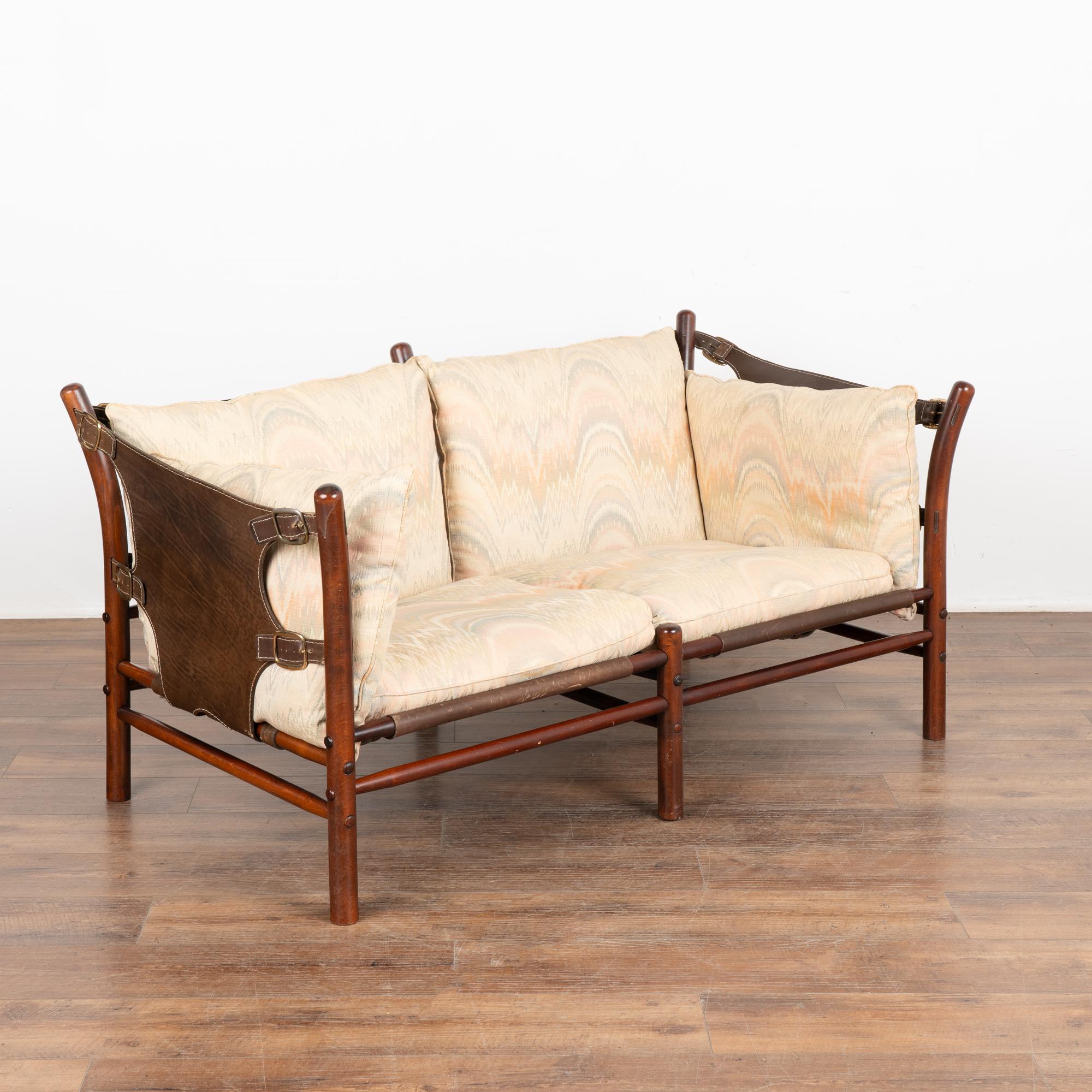 Mid-Century Modern two-person sofa designed by Arne Norell. Leather sling sides and back, brass hardware, loose cushions with zippered covers. The Ilona model was inspired by safari furniture and manufactured by Aneby Møbler (makers mark