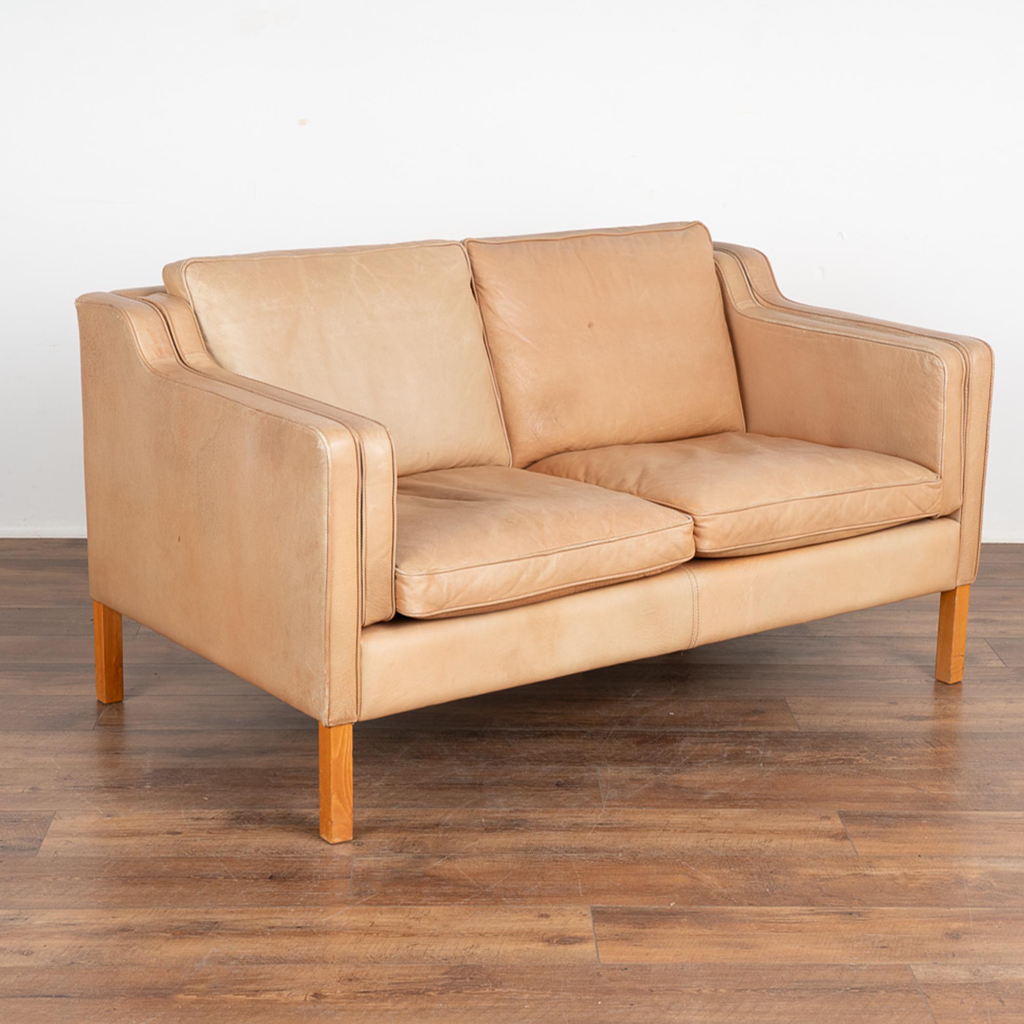 Mid-century modern vintage two seat leather Stouby sofa or loveseat from Denmark. This comfortable sofa combines tradition with modern lines.
Upholstered in camel or light brown leather, loose cushions, hardwood legs in stained beech wood. 
Sold in