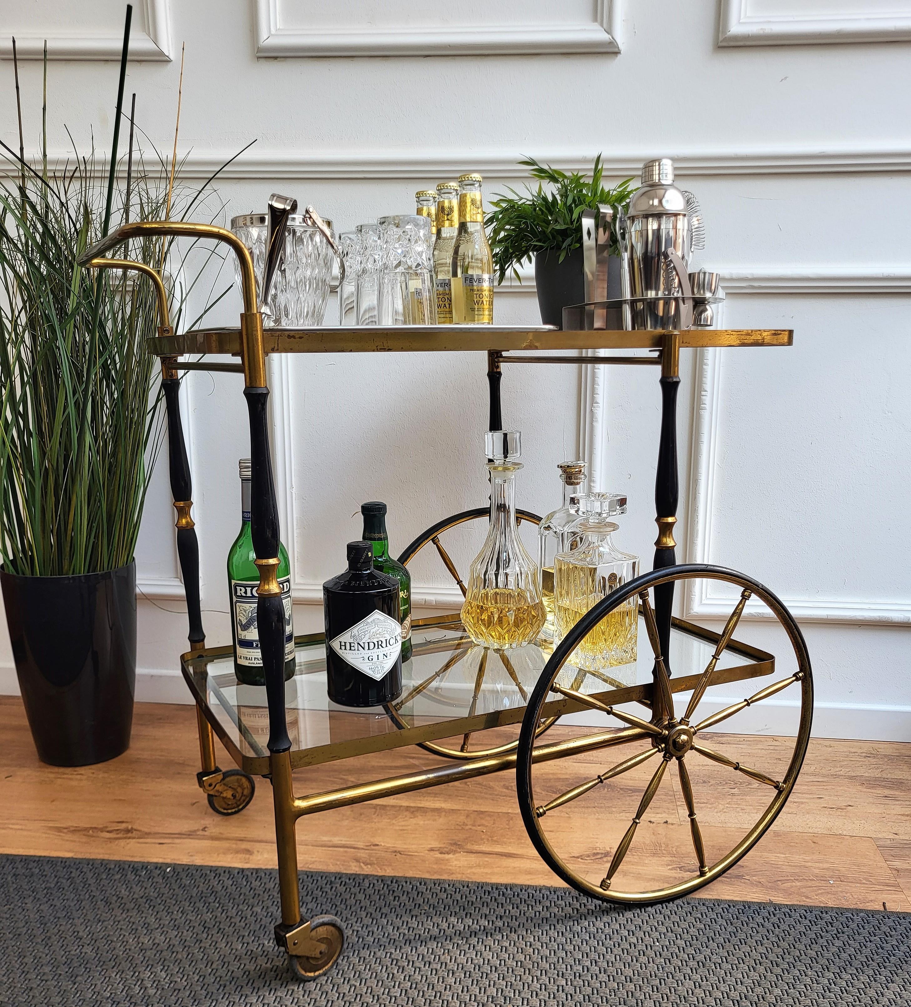 Beautiful and stylish vintage 1970s Italian two-tier brass and glass bar cart with great brass wheels. Very good condition with minor wear on the cart and tray handles. A great piece that perfectly adds to every home decor the typical glitz, glamour