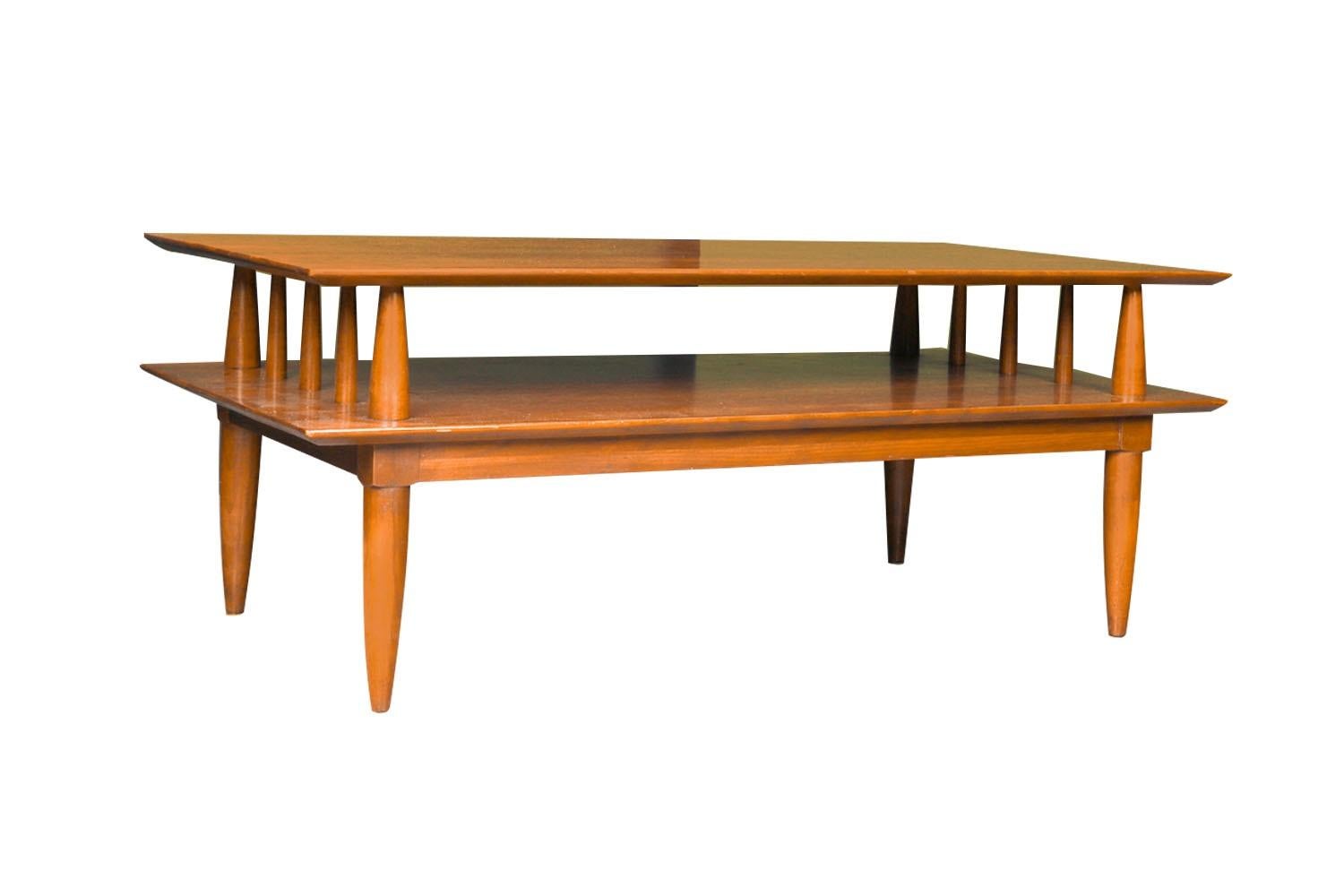 Striking architectural Mid-Century Modern two tier solid cherry coffee table by Willett furniture, circa 1960s. Solid cherry spindle support with a knife-edge top surface, the bottom shelf offers a spacious open storage area. The dramatic two tier