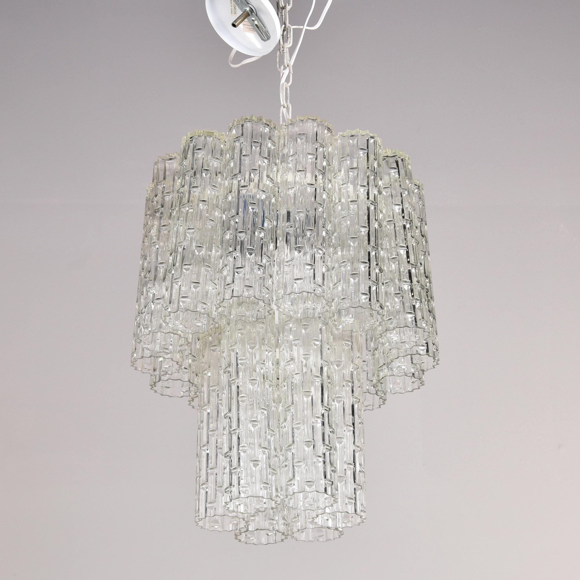 Trouvé en Italie, ce luminaire en verre à quatre lumières et à deux niveaux date des années 1960. Le cadre en métal supporte deux niveaux de pendentifs en verre moulé transparent en forme de tube avec une surface texturée. Quatre douilles de type