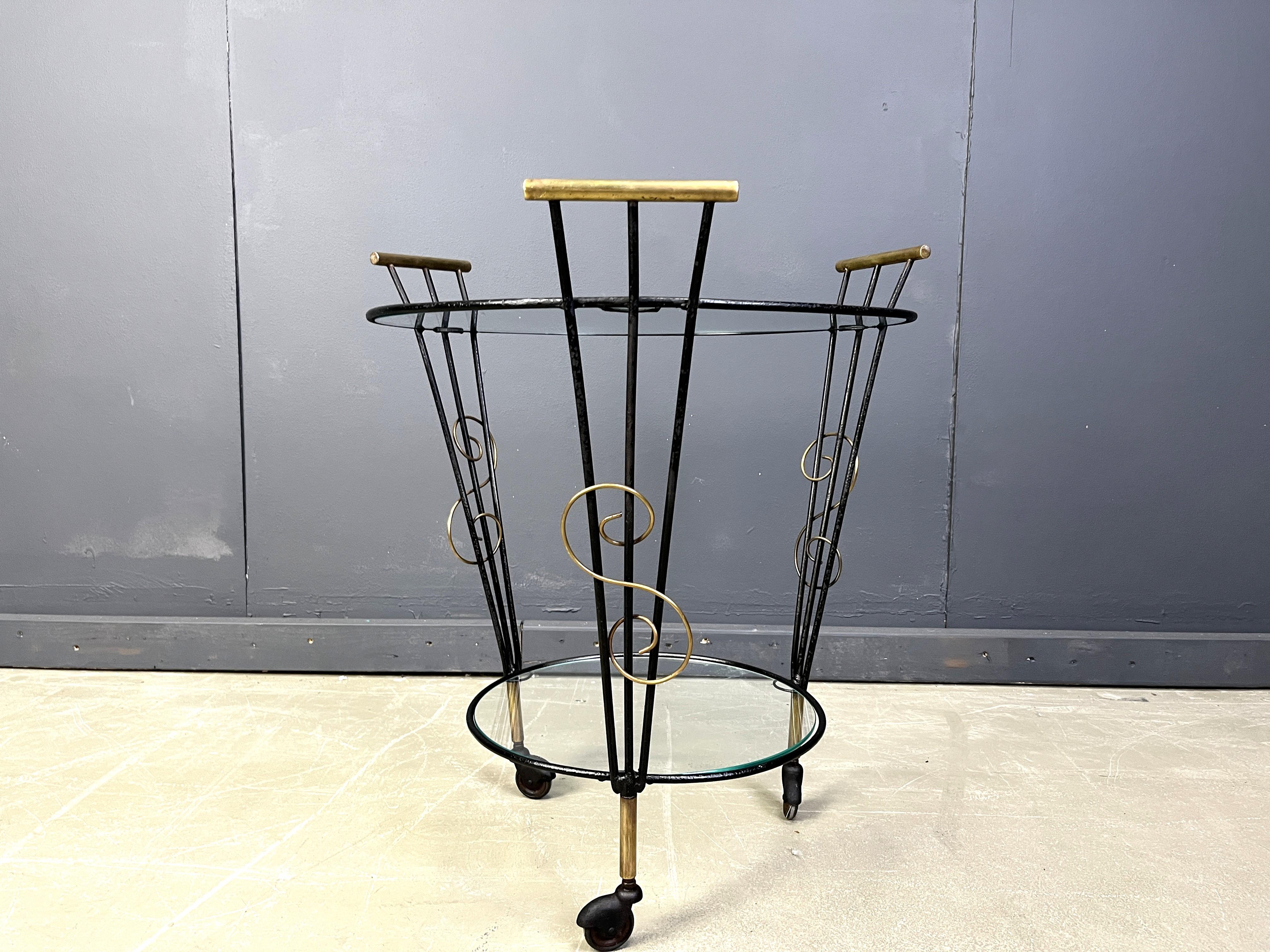 Mid century italian bar cart with a black metal frame and brass hardware. 

It has two tiers of glass shelves.

Nicely decorated serving trolley with a touch of  mid century italian elegance 

1950s - Italy

Dimensions:
Height: 68cm
Diameter: