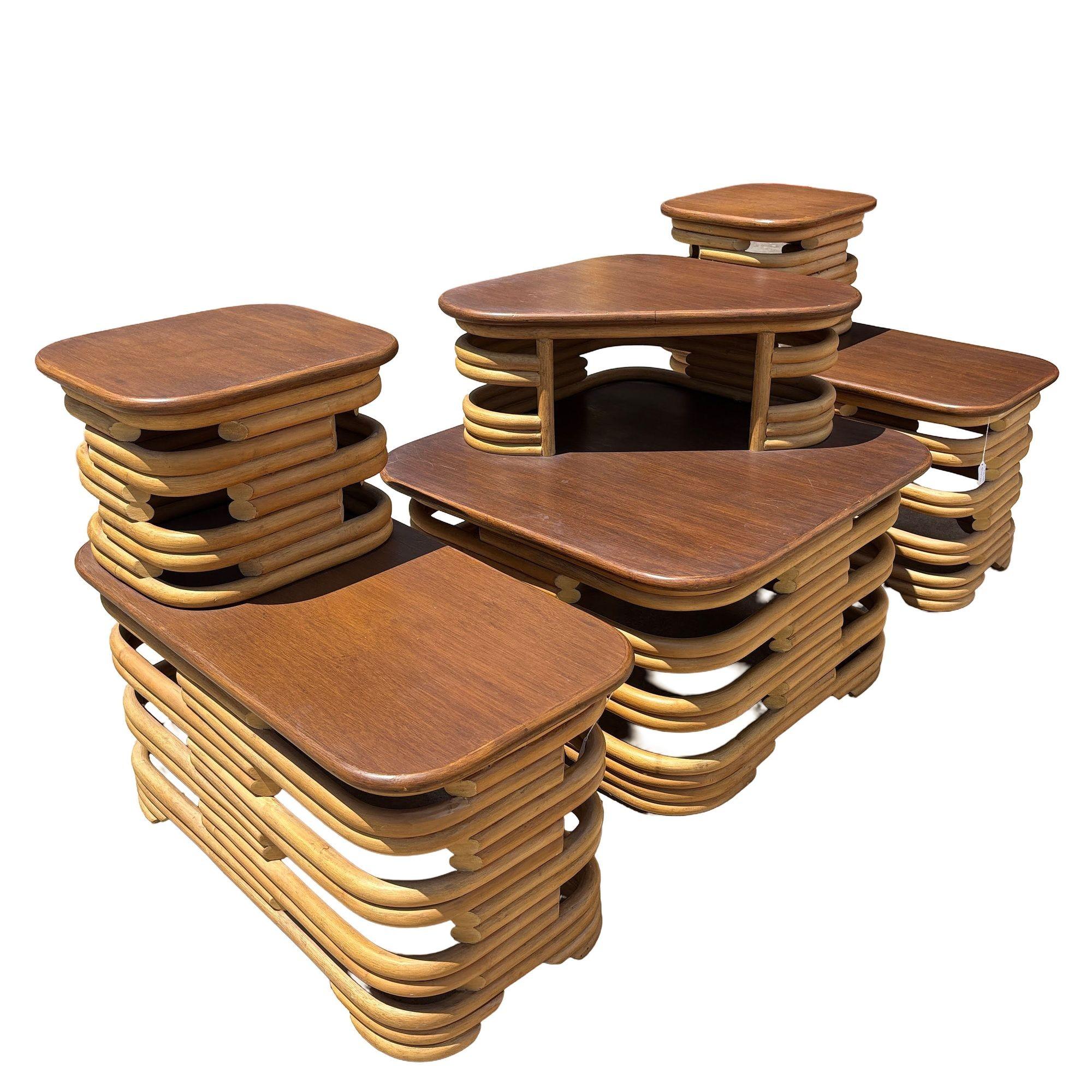 Cette paire de tables d'appoint en rotin empilées à deux niveaux et table d'angle incluse avec des côtés découpés, chacune avec un plateau en bois d'acajou flammé, a été magnifiquement restaurée au milieu du siècle. Ces pièces d'inspiration vintage