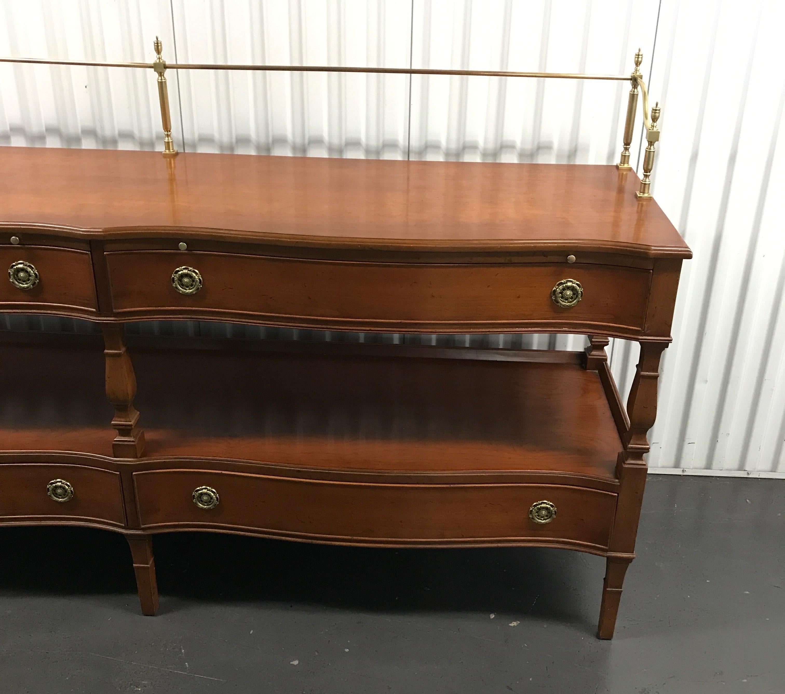 Two tier brass galleried serpentine sideboard with four drawers. Height to top of brass gallery is 42.75.