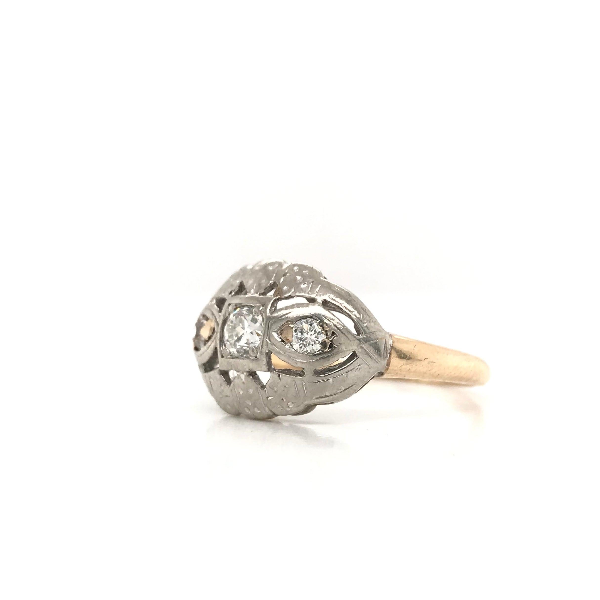 This piece was crafted sometime during the Mid Century design period ( 1940-1960 ). The setting features a 14k yellow gold shank with a distinctive 14k white gold head. The setting features basic filigree, subtle engravings and three diamond