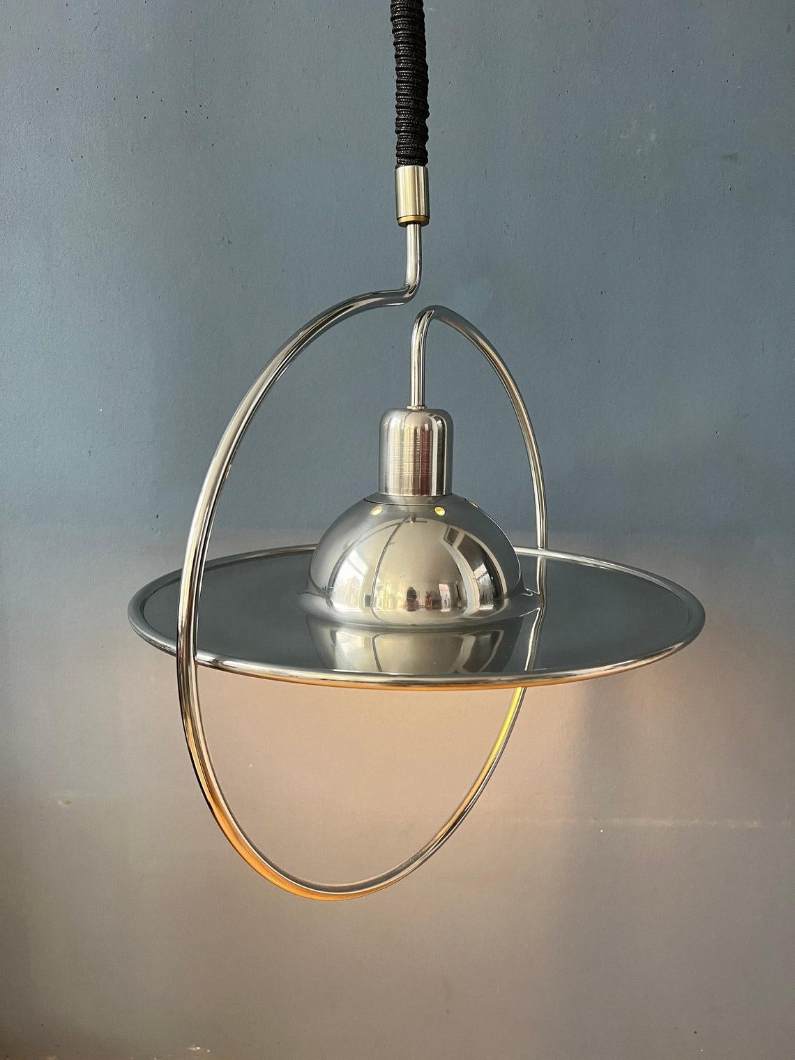 Mid century UFO pendant lamp with decorative chrome frame. The height of the lamp can easily be adjusted with the suspension mechanism. The lamp requires one E27/26 (standard) lightbulb.

Additional information:
Materials: Metal
Period: