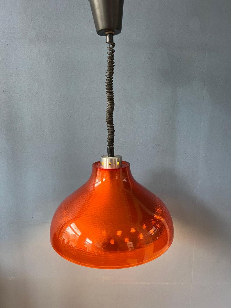 Lampada a sospensione di metà secolo in plexiglass arancione dell'era spaziale. La lampada ha un paralume esterno arancione e un paralume interno in alluminio a fantasia. Insieme creano una magnifica luce 