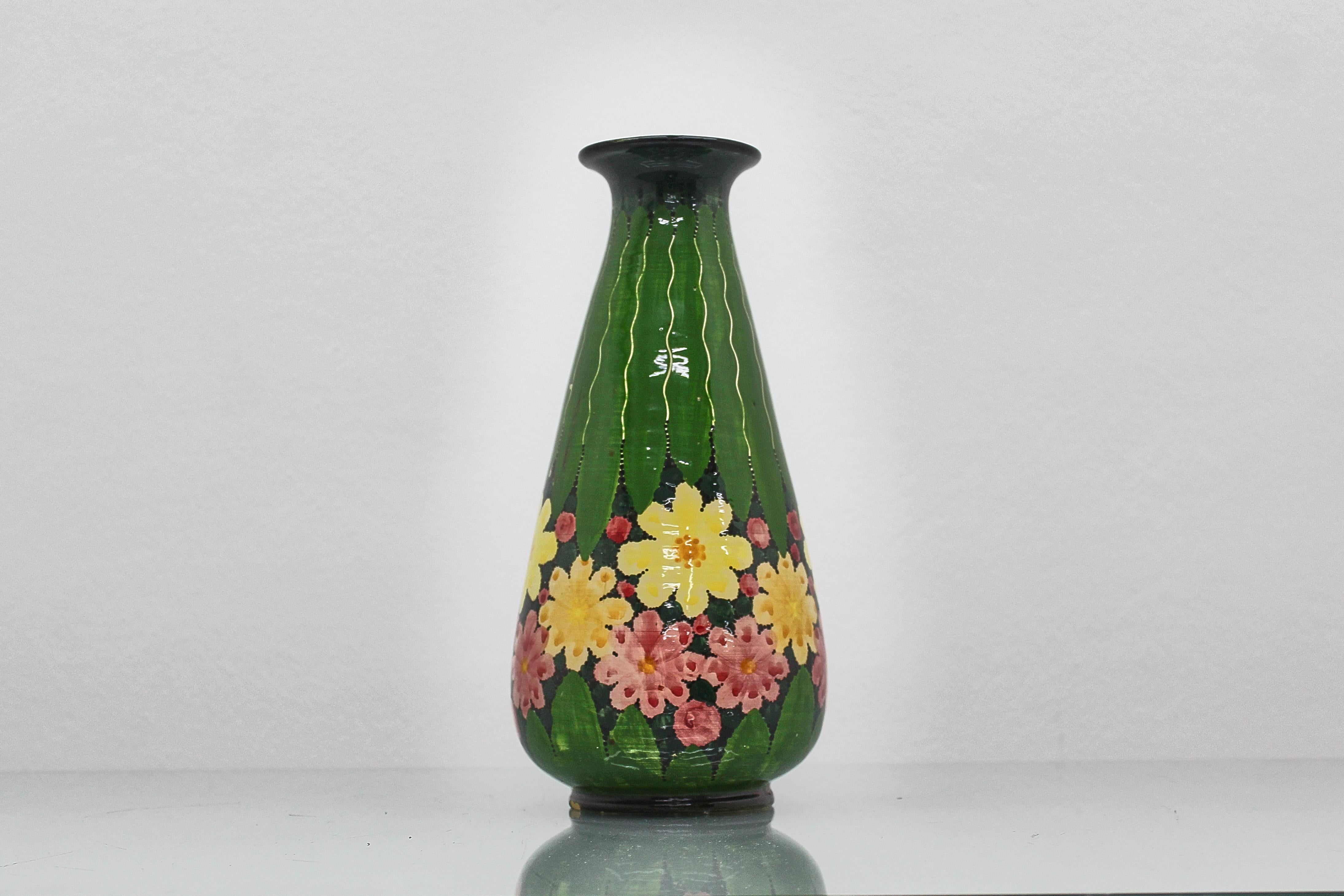 Délicieux vase en céramique émaillée avec des décorations florales polychromes stylisées à la main. Le fond porte la signature de la manufacture 