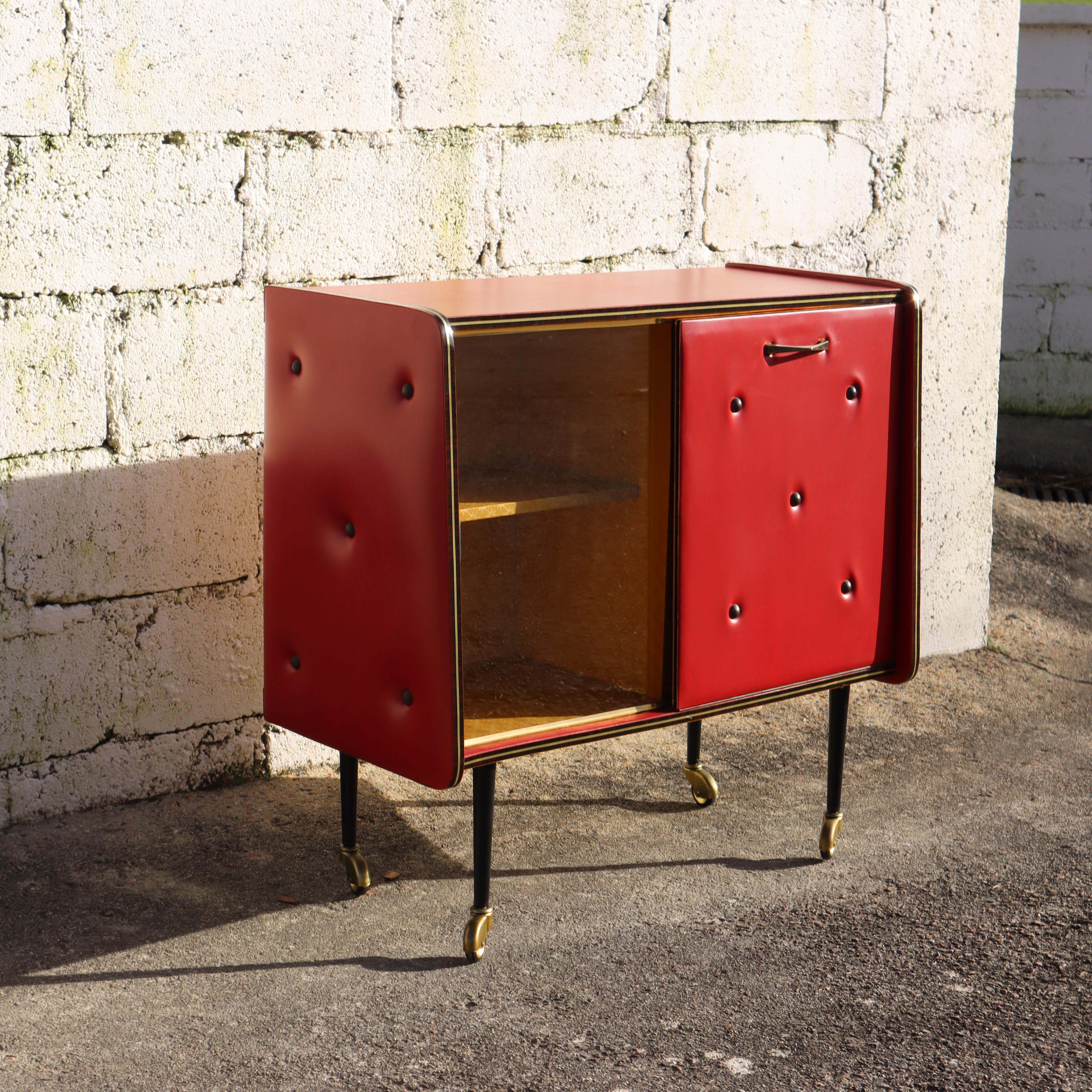 Rare Beautiful Mid-Century upholstered red Skai Leather Bar Trolley from the 50s
Real Mid-Century - Handmade mobile Bar - Sides and Front made of thickly padded Faux Leather in Chesterfield Style.

The interior of the bar cart is lined with very