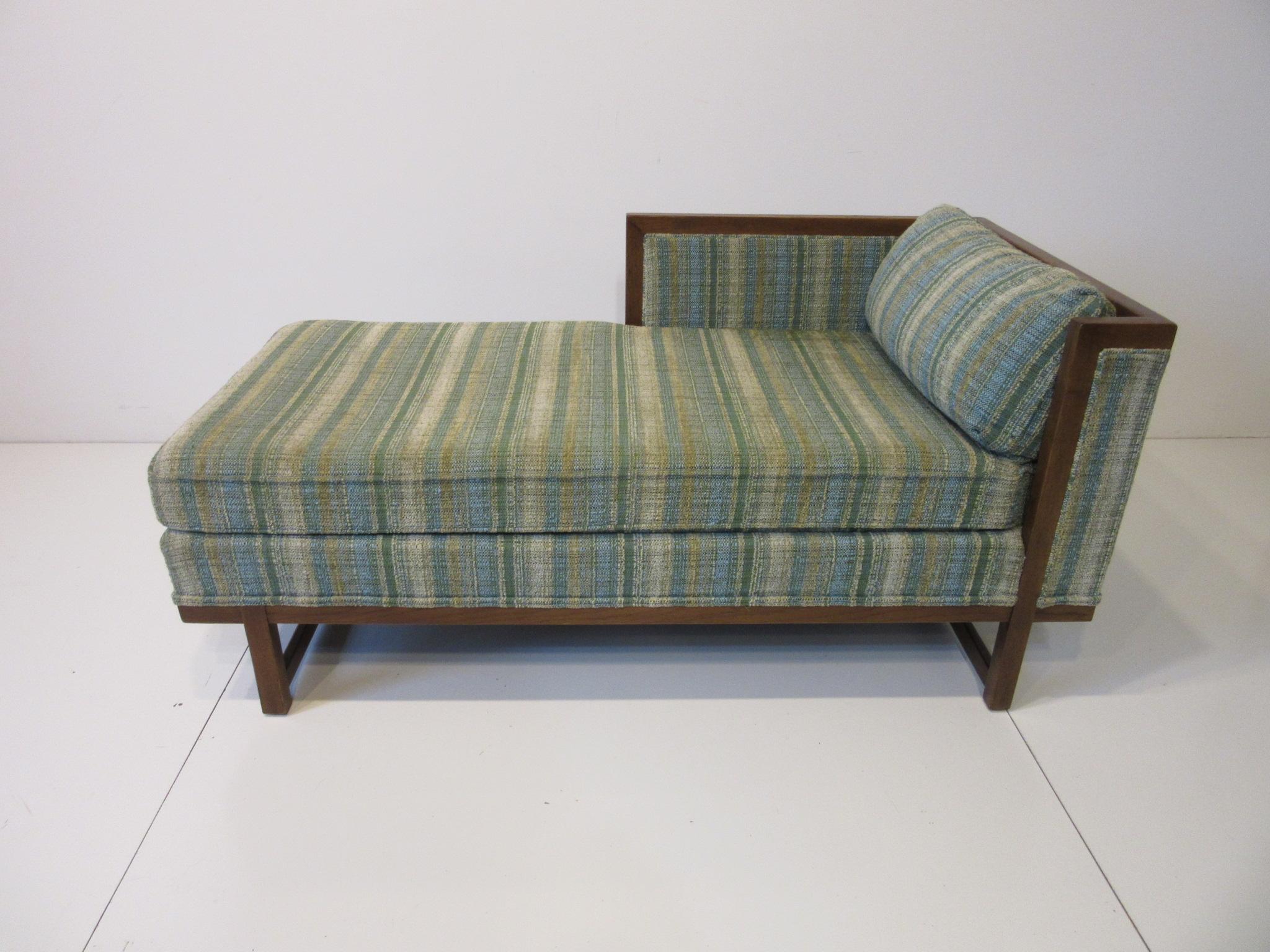 A very well crafted midcentury chaise lounge chair with green/ sea blue and taupe upholstery with matching back pillow. The medium dark wood frame with lower stretchers and upper support to the side and back making a tight and refined look.
