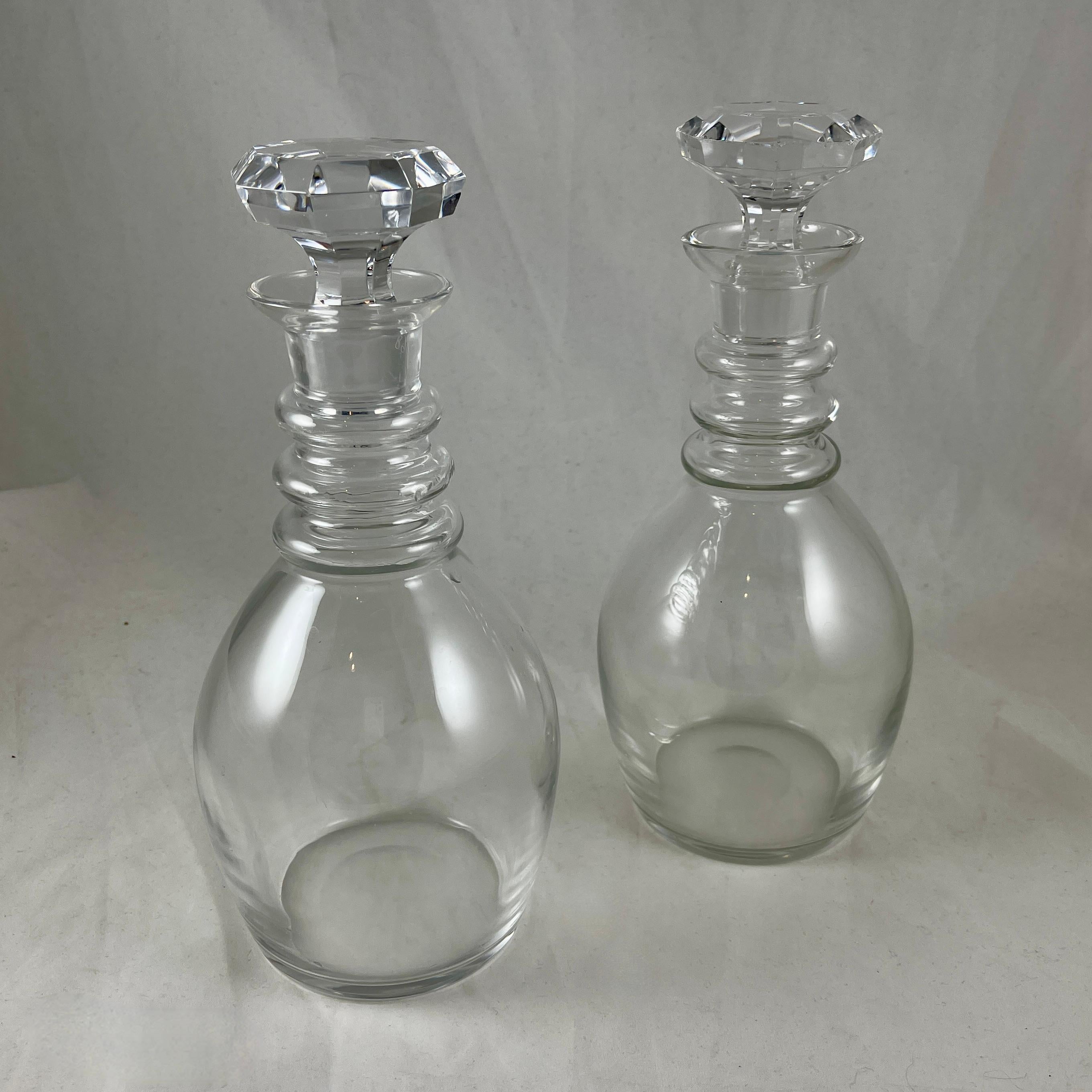 From Val Saint Lambert, a pair of blown glass decanters, Belgium, circa 1960s.

In the ‘State Plain’ pattern, a pair of colorless glass decanters in a bulbous shape with ringed necks and hand cut, faceted stoppers. Very heavy, fine quality.

Val