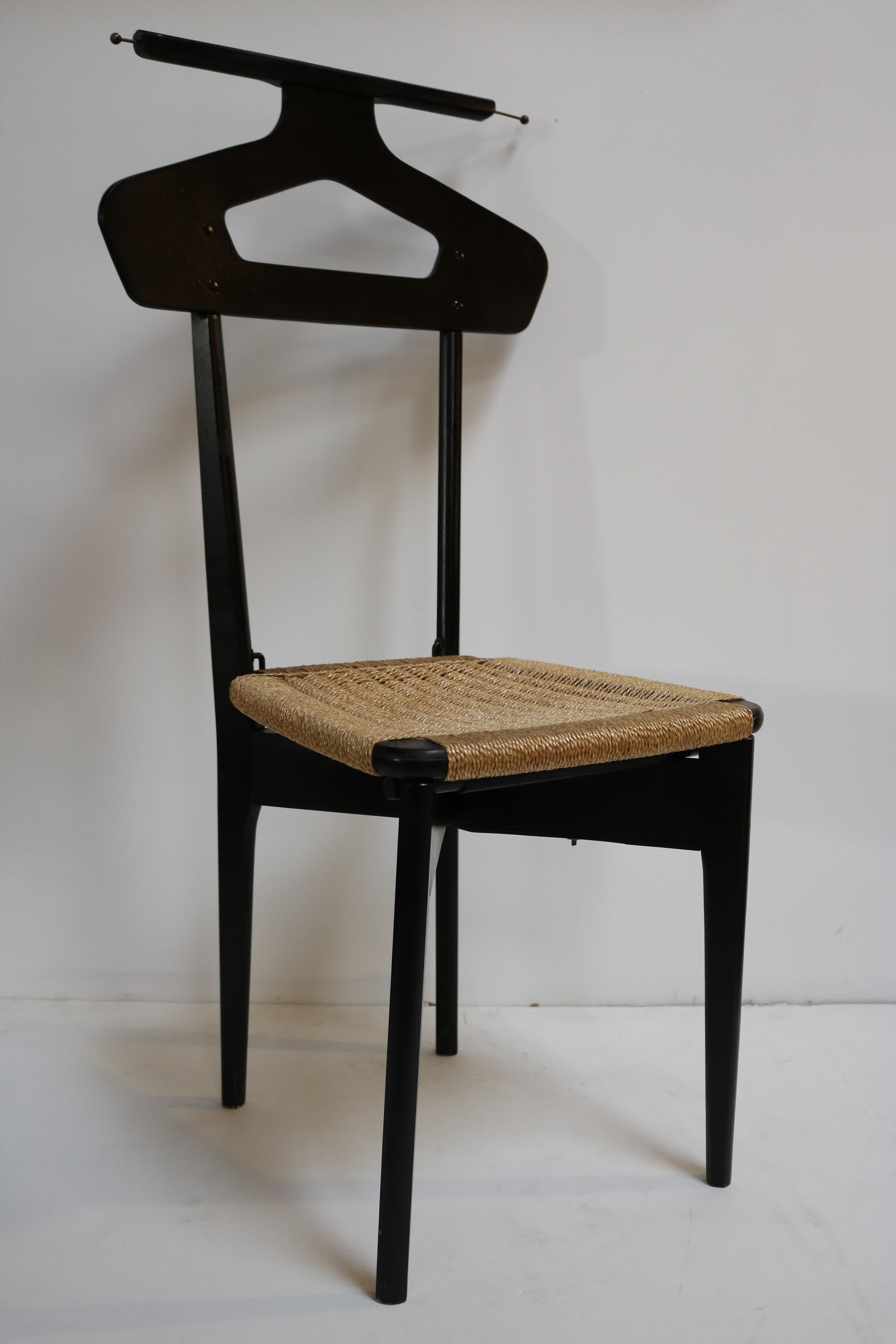 This valet is of black stained wood.
The seat and the top are covered with cane.
On each side of the top, there is a brass retractable rod to hang your tie, belt or scarf.
If you lift the seat open, you'll find a secret compartment where you can