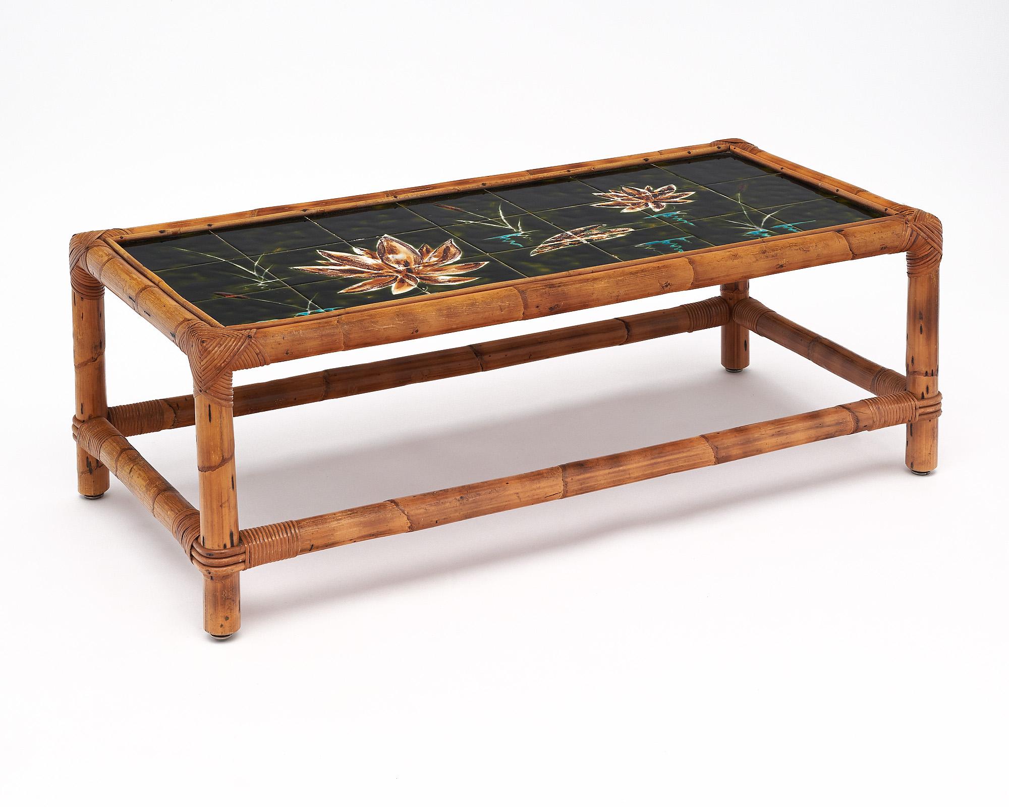 Coffee table from mid-century France. The structure is made of bamboo, while the top is tiled with tiles from Vallauris. The tiles showcase a hand-painted design of lilies.
