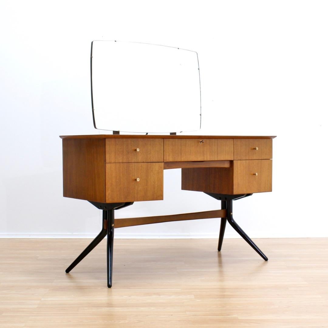 Questo splendido vanity di metà secolo è stato prodotto da Wrighton Furniture negli anni Cinquanta. Un pezzo forte della camera da letto con struttura in ebano, specchio regolabile e cinque cassetti per un ampio spazio di archiviazione. Con un