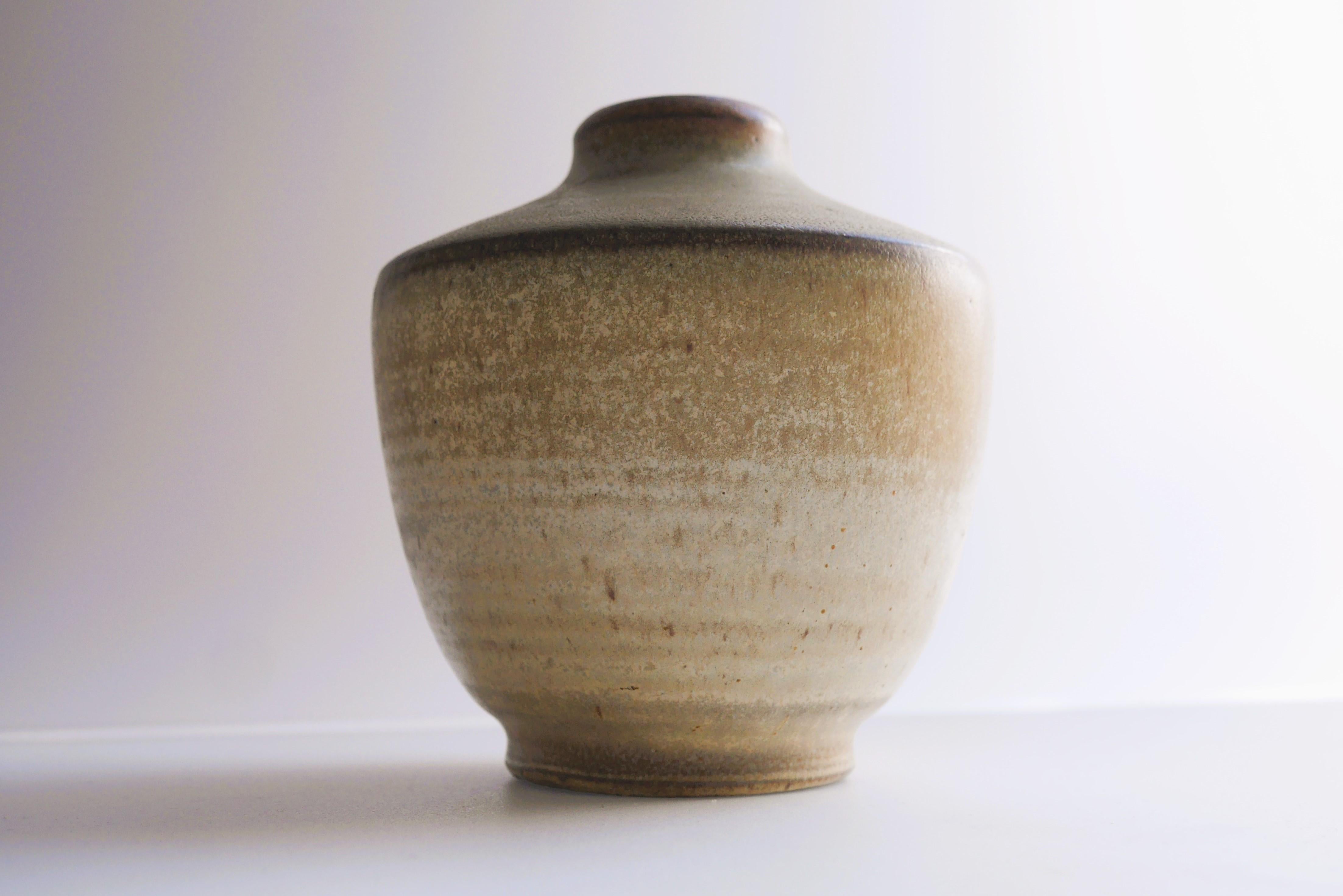 Un fantastique vase vintage en céramique, fait et dessiné à la main par Arthur Andersson, pour Wallåkra Keramik, Suède. Le vase a une belle couleur, un brun pâle ou beige, avec des touches de moutarde, un glaçage simple mais efficace, avec un effet