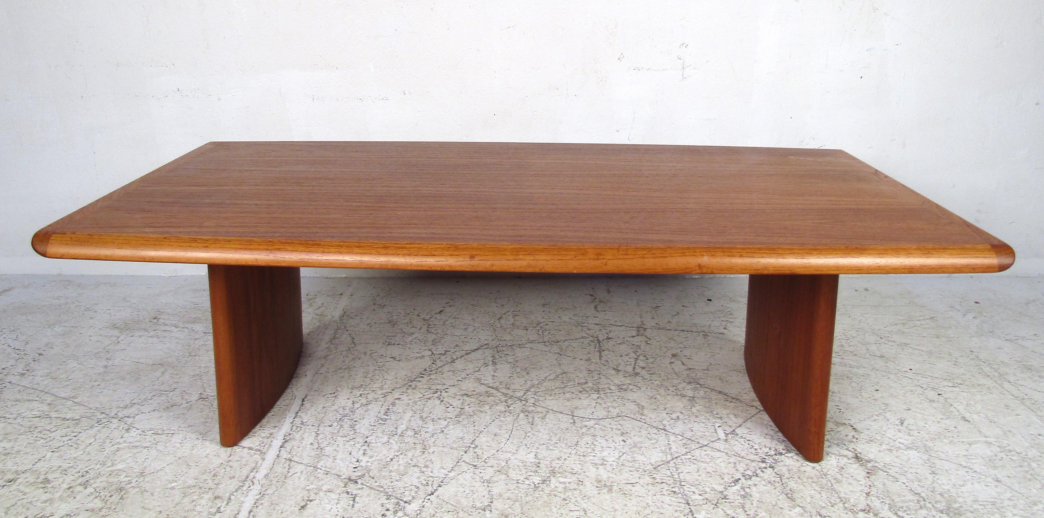 This stunning vintage modern coffee table features unusual ellipse-shaped legs and smooth edges along the top. A rich teak finish and sturdy construction make this table appeal to any home, business, or office. An original case piece with a stamp on