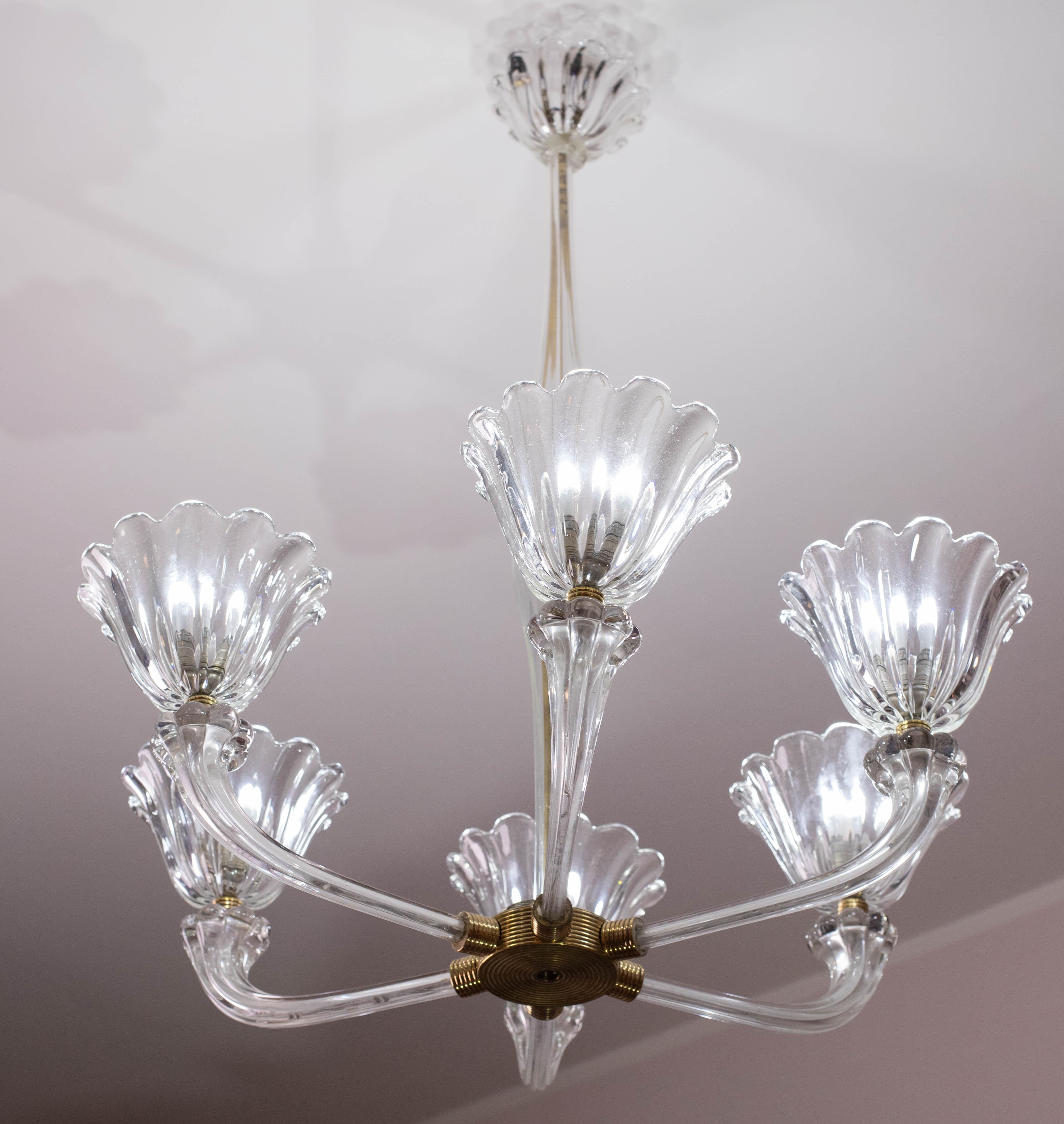Stupendo lampadario a sei luci in stile Art Déco veneziano di metà secolo, realizzato in ottone e vetro soffiato smerlato trasparente.
Periodo di produzione 1940-50, attribuibile alla vetreria Seguso.
Tutte le parti in ottone sono state