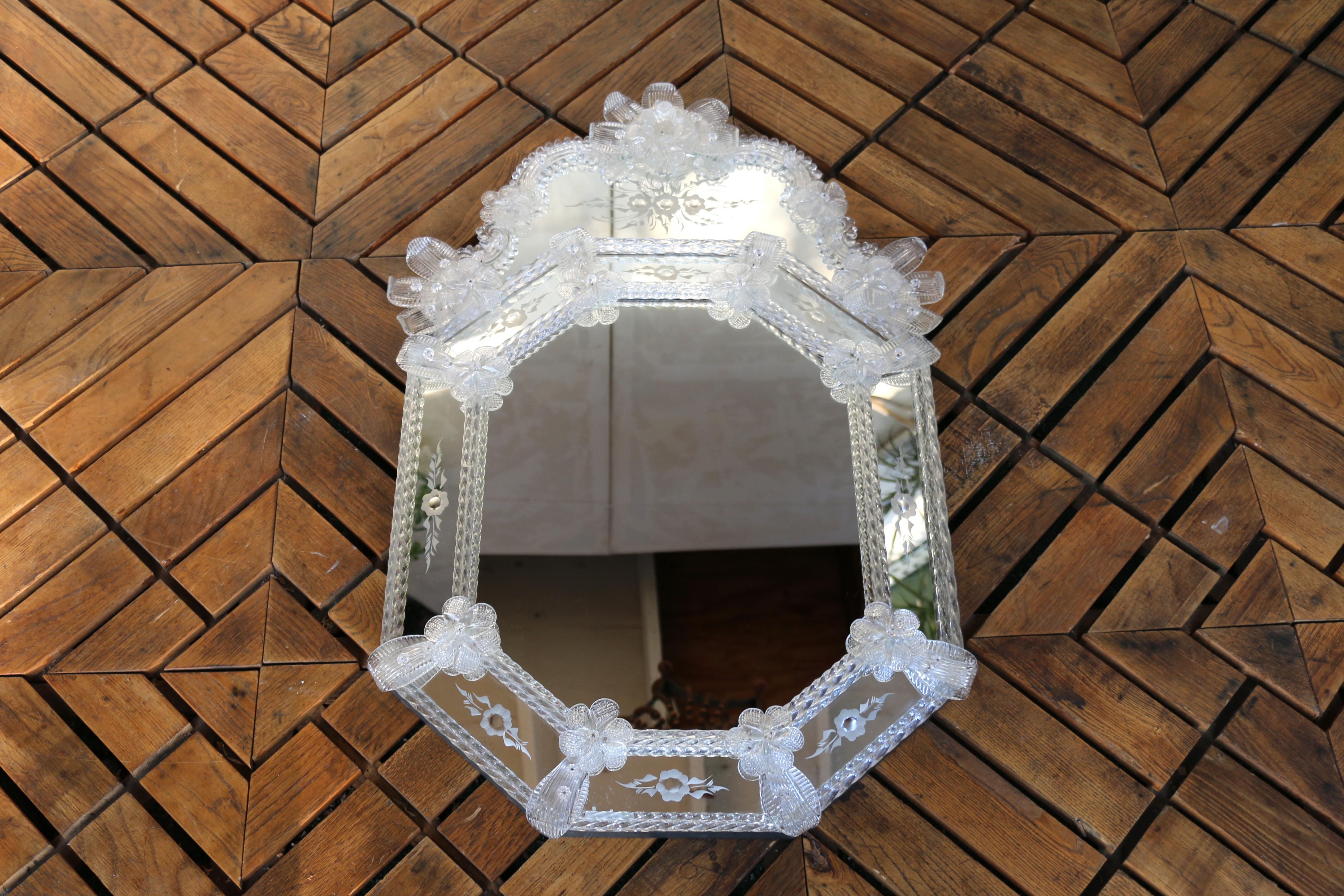 Ein raffinierter venezianischer Spiegel, handgefertigt in Murano, Italien, ca. 1980er Jahre. Dieses exquisite Stück zeichnet sich durch einen anmutig geformten Rahmen aus, der aus einzeln abgeschrägten und geätzten Glasscheiben besteht, die mit