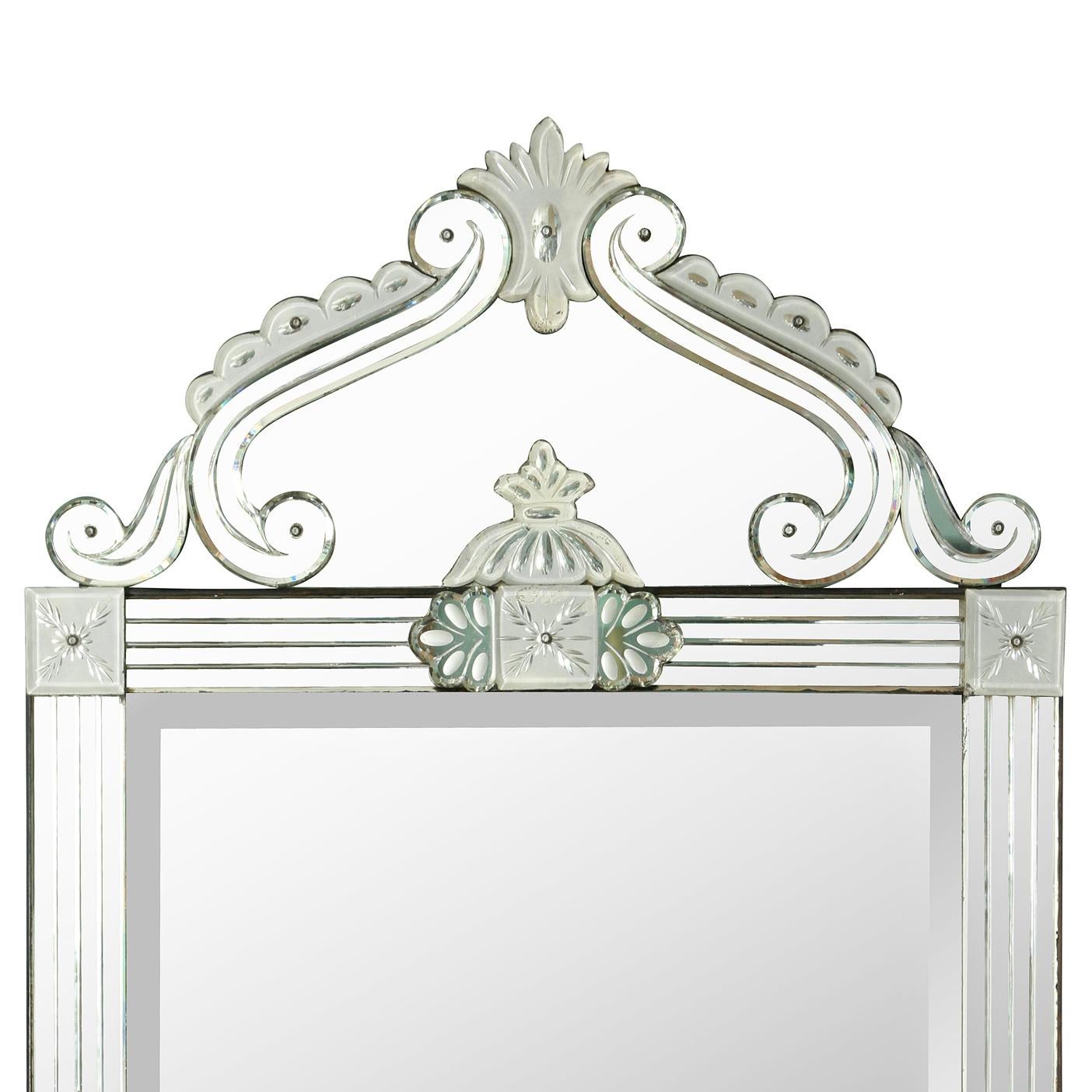 A rectangular Venetian style beveled mirror with foliate details and a mirrored swirled crest at top.  The mirror frame features a  ribbed design with a foliate motif at each corner and the center of each of the four sides.  The Mid Century mirror 