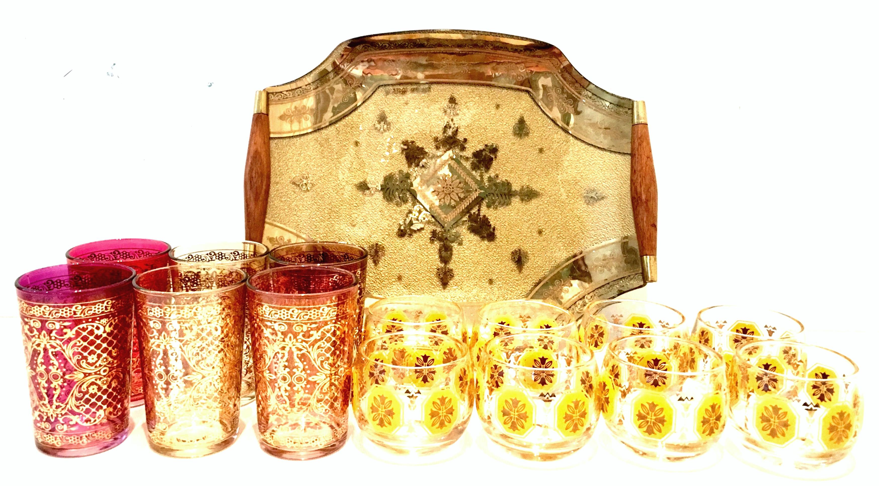 Mid-20th Century Venetian 22-karat gold drinks set and tray of 15 pieces by, Georges Briard. This set includes a reverse painted glass teak and gilt brass handle tray signed, Georges Briard, eight printed glass, 