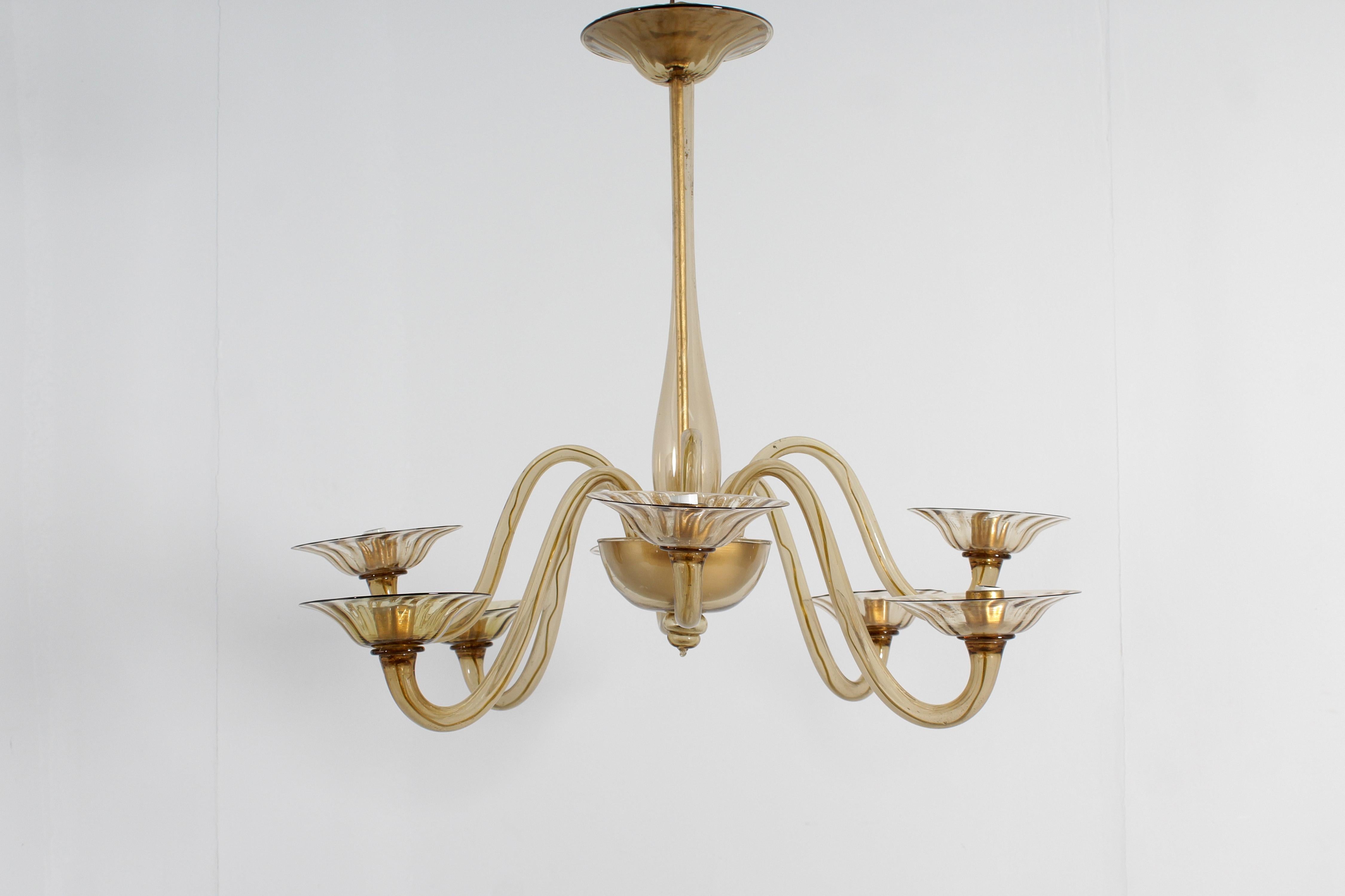 Very beautiful and elegant eight-arm chandelier with a classic venetian design in Murano glass. Entirely in amber hand-blown glass, with eight curved arms and a central body in smooth glass, lamp holder cups and glass rosette with hints of ribs. Rod