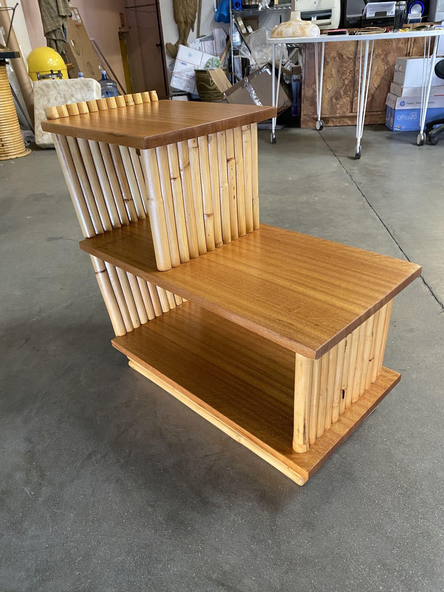 Paul Frankl style three-tier vertically stacked rattan end table pair with stained mahogany wood tops, circa 1950.
 
We only purchase and sell only the best and finest rattan furniture made by the best and most well-known American designers and