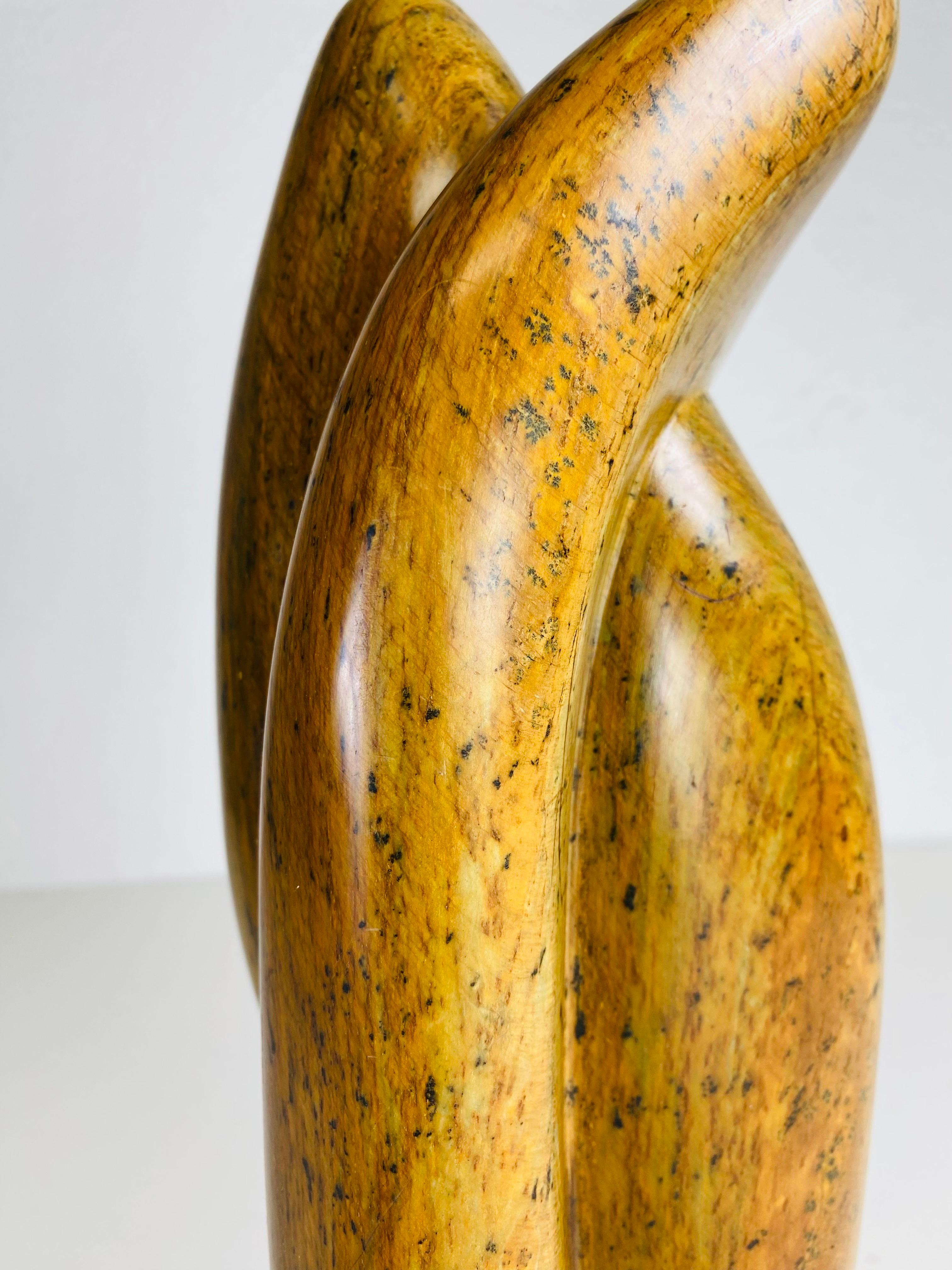 This is a mid century vintage abstract stone sculpture. This hand carved smoothly polished amber stone stands on a Lucite plinth. This stone sculpture has beautiful tones of amber, dark brown and black throughout the sculpture. The sculpture is
