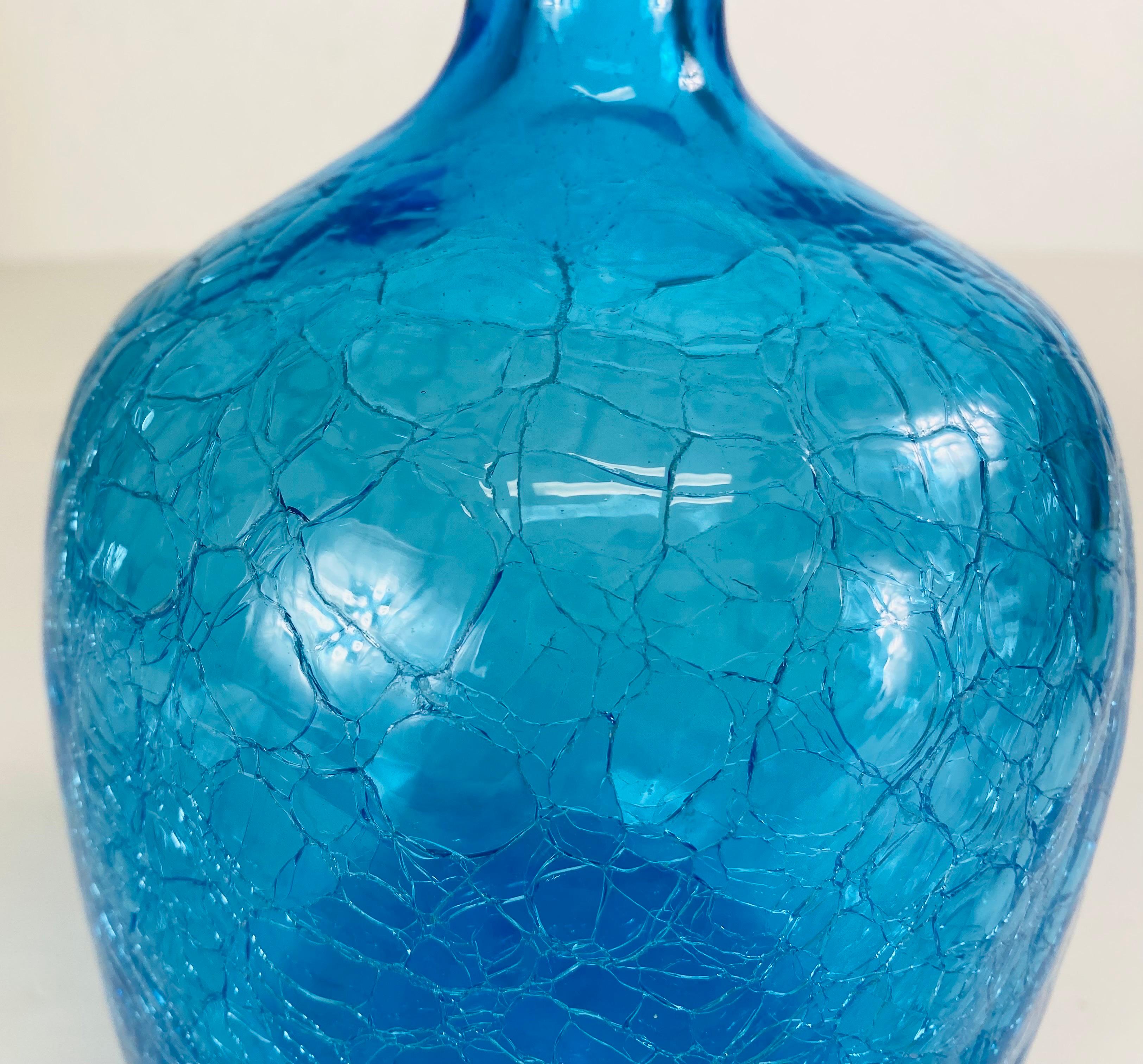 This is a large mid-century vintage Blenko blue glass jar with his original stopper. This blue jar has a heavily crackled finish of the surface and is complete with its original tall blue stopper. The Blanco jar and stopper is American made circa