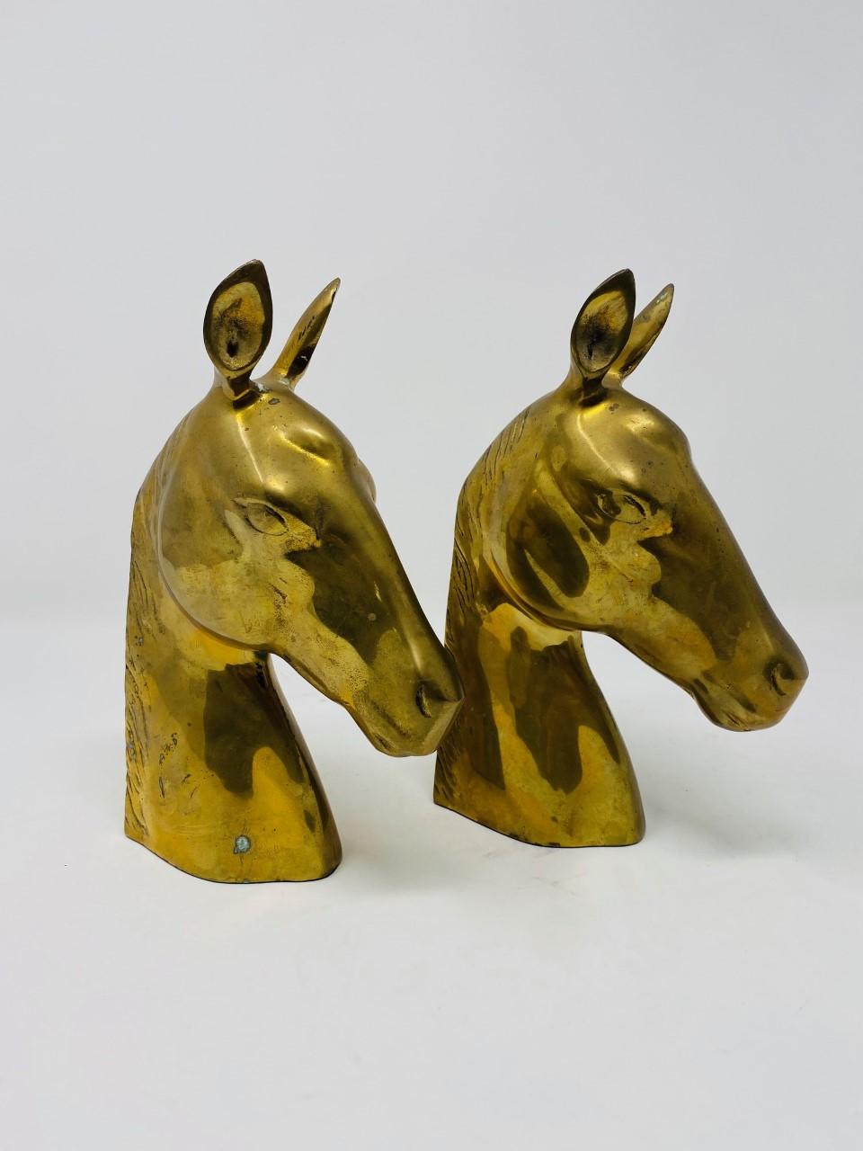 Striking pair of vintage brass horse head bookends with beautiful patina. The details on the figures evoke elegance and nostalgia. Perfect for your mid-century or Hollywood Regency decor styles. Incredible sculptural renditions that will bring