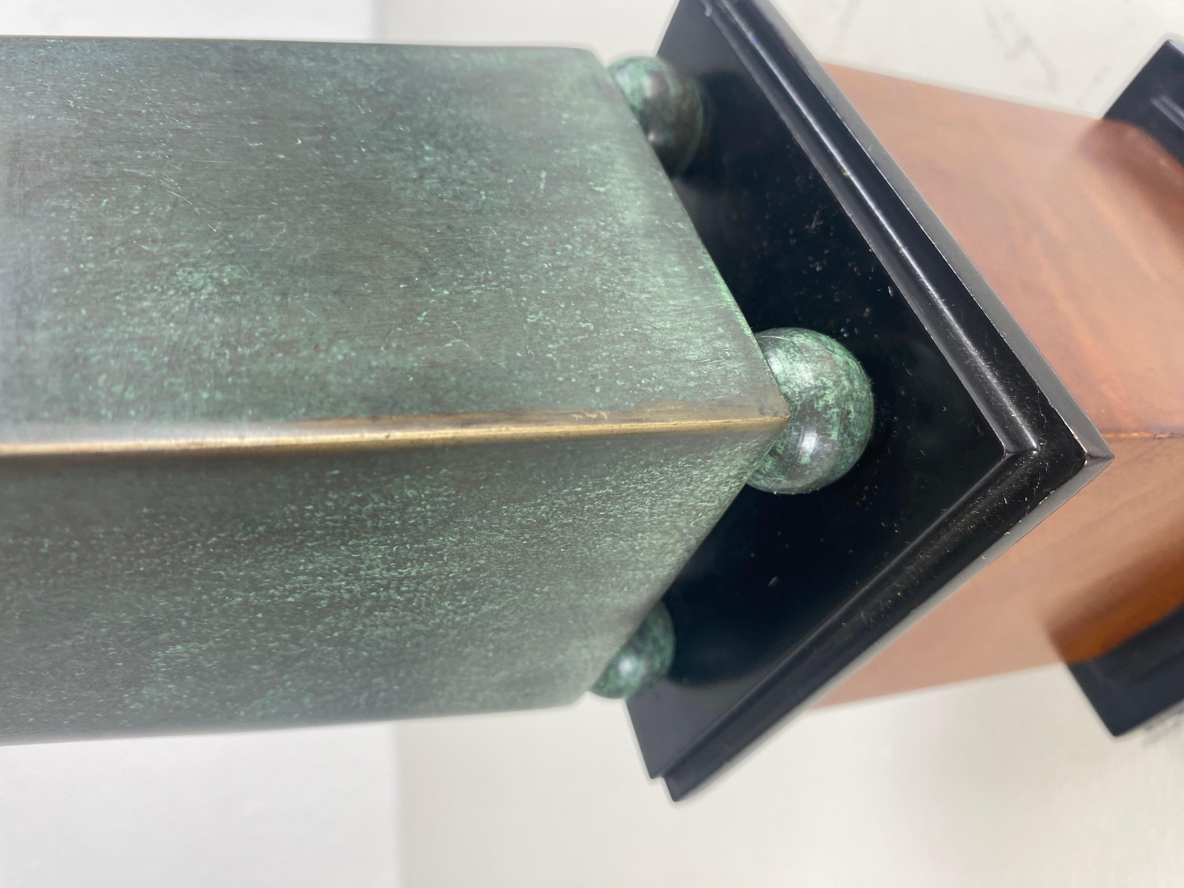 This is a handsome mid century vintage bronze obelisk. This bronze obelisk stands on fort ball feet that stands on a black Lacquered and walnut plant. This bronze obelisk has a dark burnish patina that is appropriate for its age in history. This