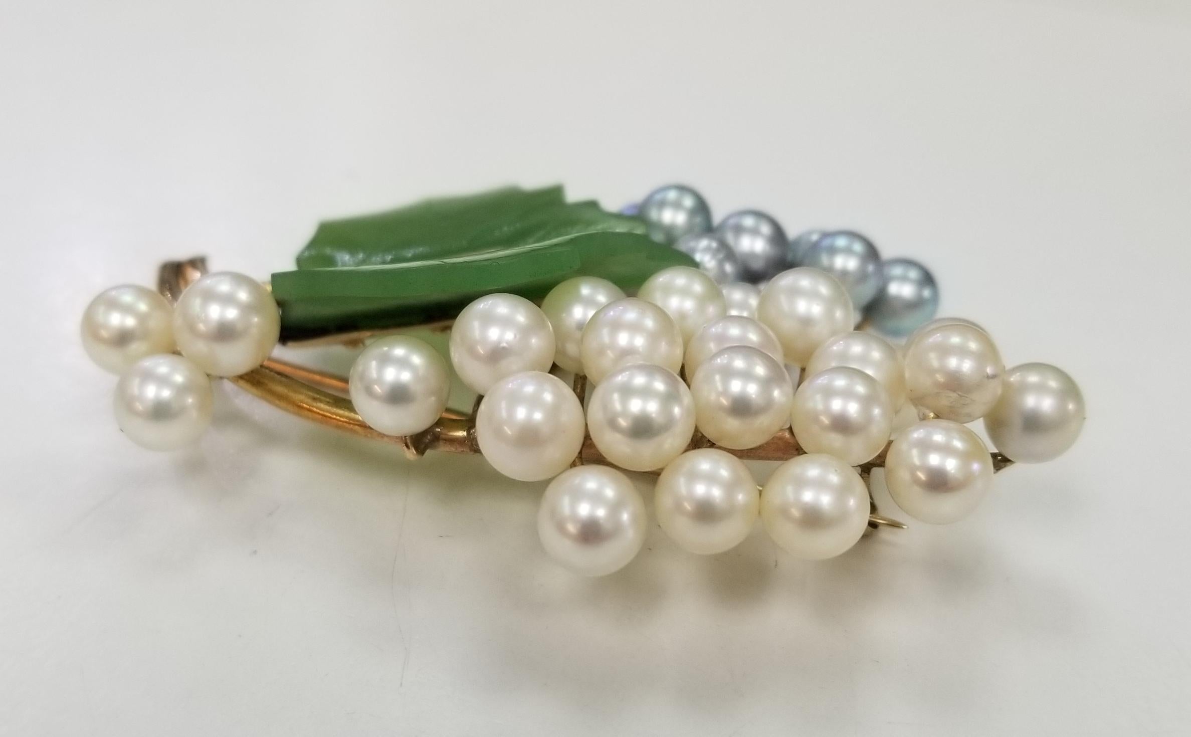 This gorgeous, Mid Century vintage brooch,  features carved nephrite and pearls in a 14 karat gold floral motif. 
There are two (2) carved nephrite jade leaves, each carved by hand and 37 pearls measuring 5-6mm(the piece is old enough that the