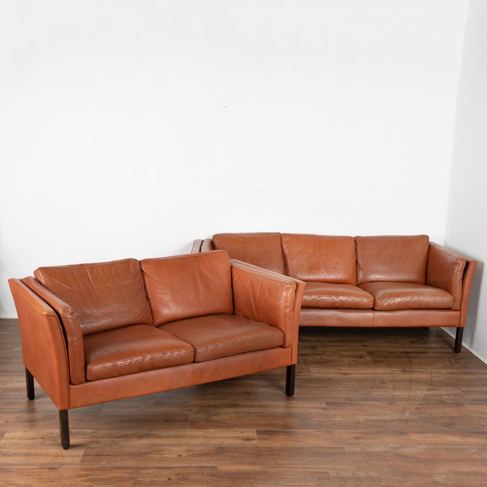Mid-Century Modern three-seat sofa and two-seat loveseat set.
Upholstered in cognac-colored leather, loose cushions on the sides, seat and back.
Dimensions:
3 Seat Sofa: 77.25X31.25X28 Seat H: 17in.
2 Seat Sofa: 56.5X31X28 Seat H: 17in.
Sold in