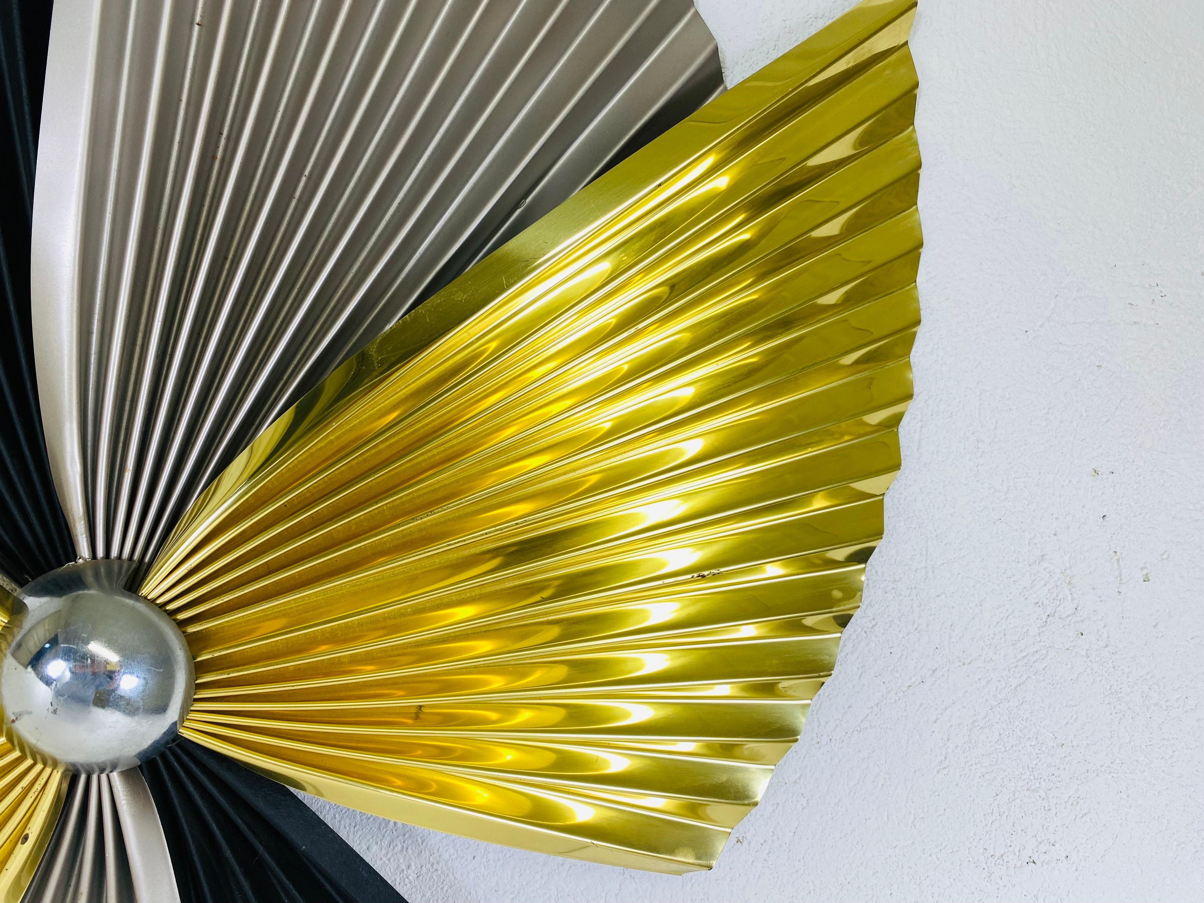 This is a mid century vintage brass and steel wall sculpture by Curtis jere. This wall sculpture has an Asian inspiration with pleated fans in brass, black and silver steel. This wall sculpture has its original documentation on the reverse.
