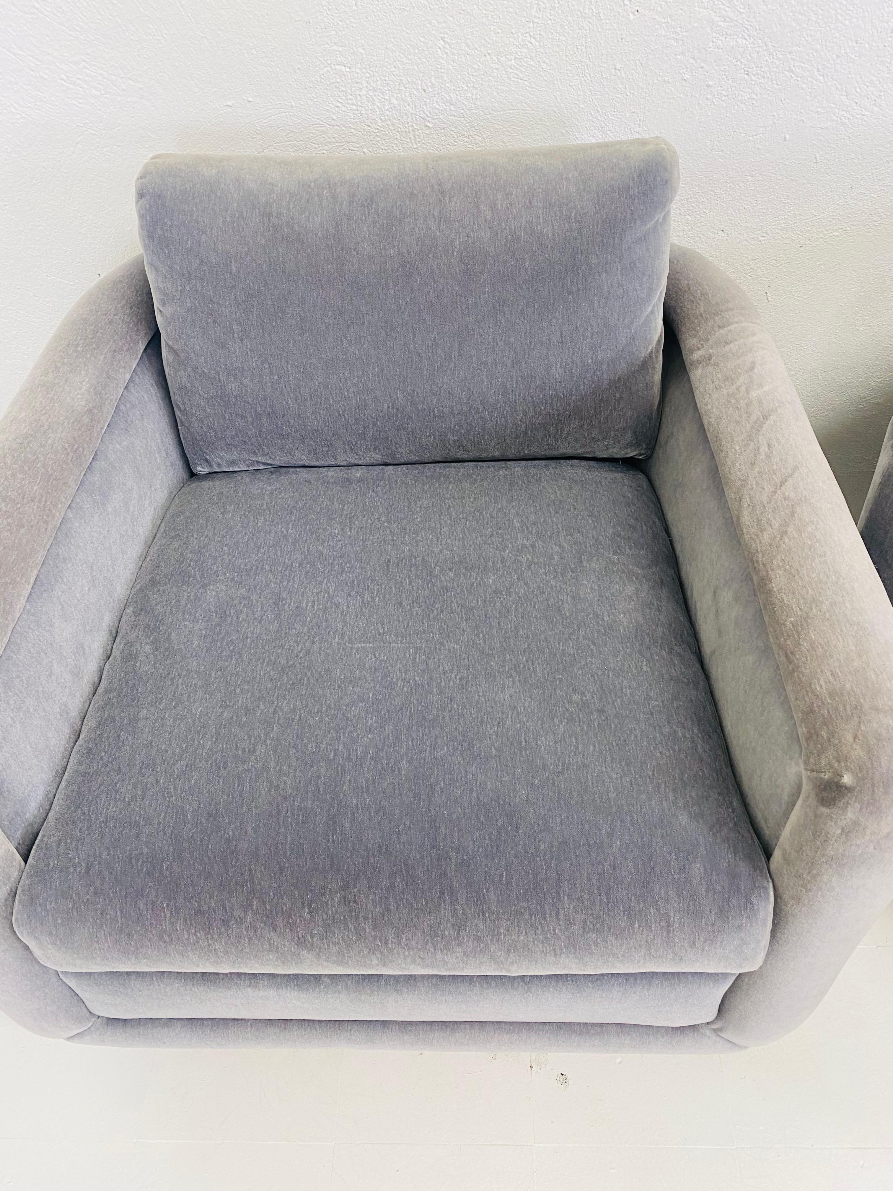 This is a pair of mid-century vintage plush Mohair club chairs. These deco inspired club chairs are upholstered in their original Italian gray plush mohair fabric and stand on a light wood platform. This pair of bespoke chairs are American made