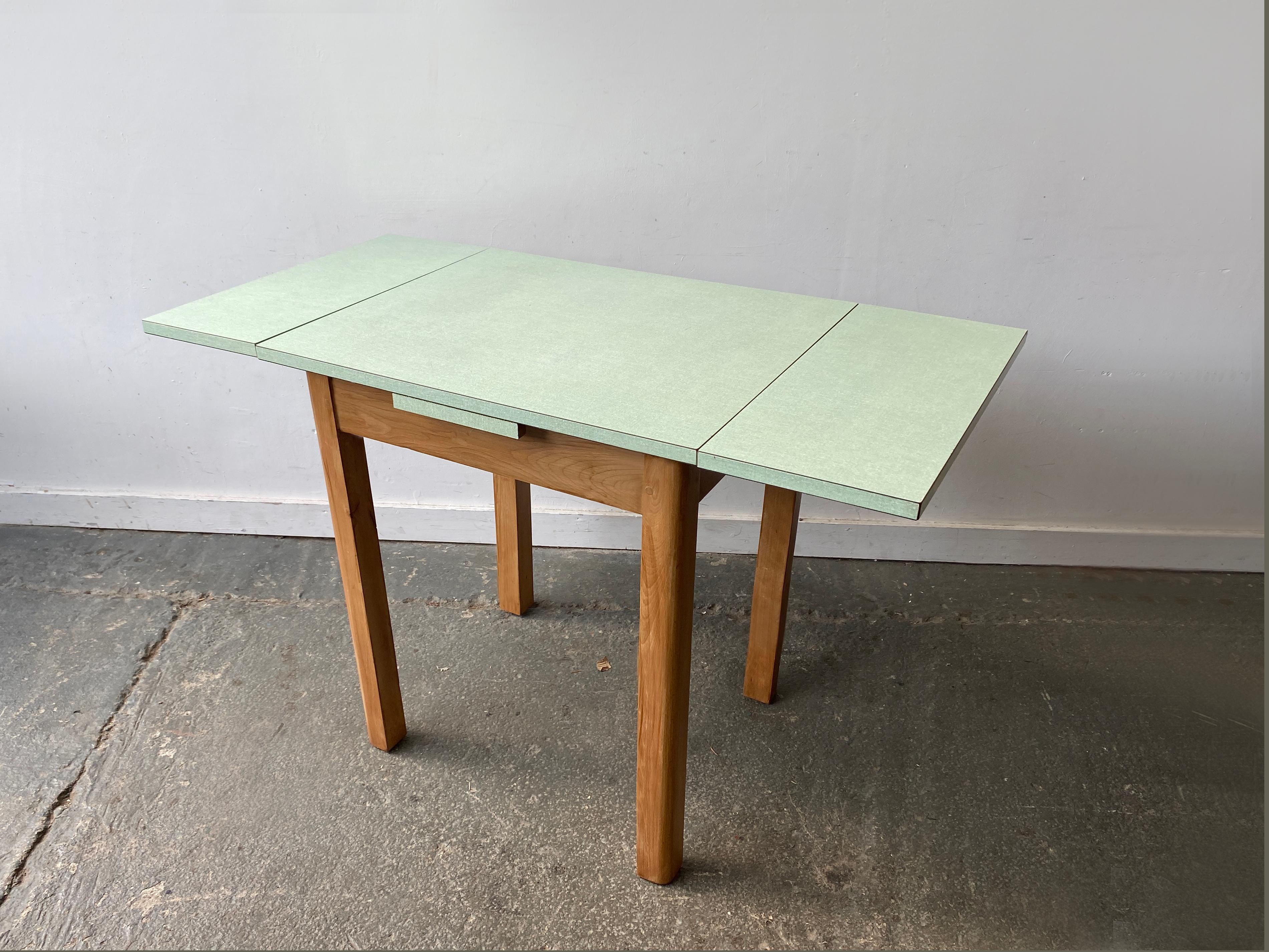 Petite table de salle à manger du milieu du siècle, idéalement pratique et élégante, datant des années 1950-1960. Une pièce polyvalente, idéale pour les cuisines ou les salles à manger compactes.

Il se compose d'un plateau en formica vert pâle