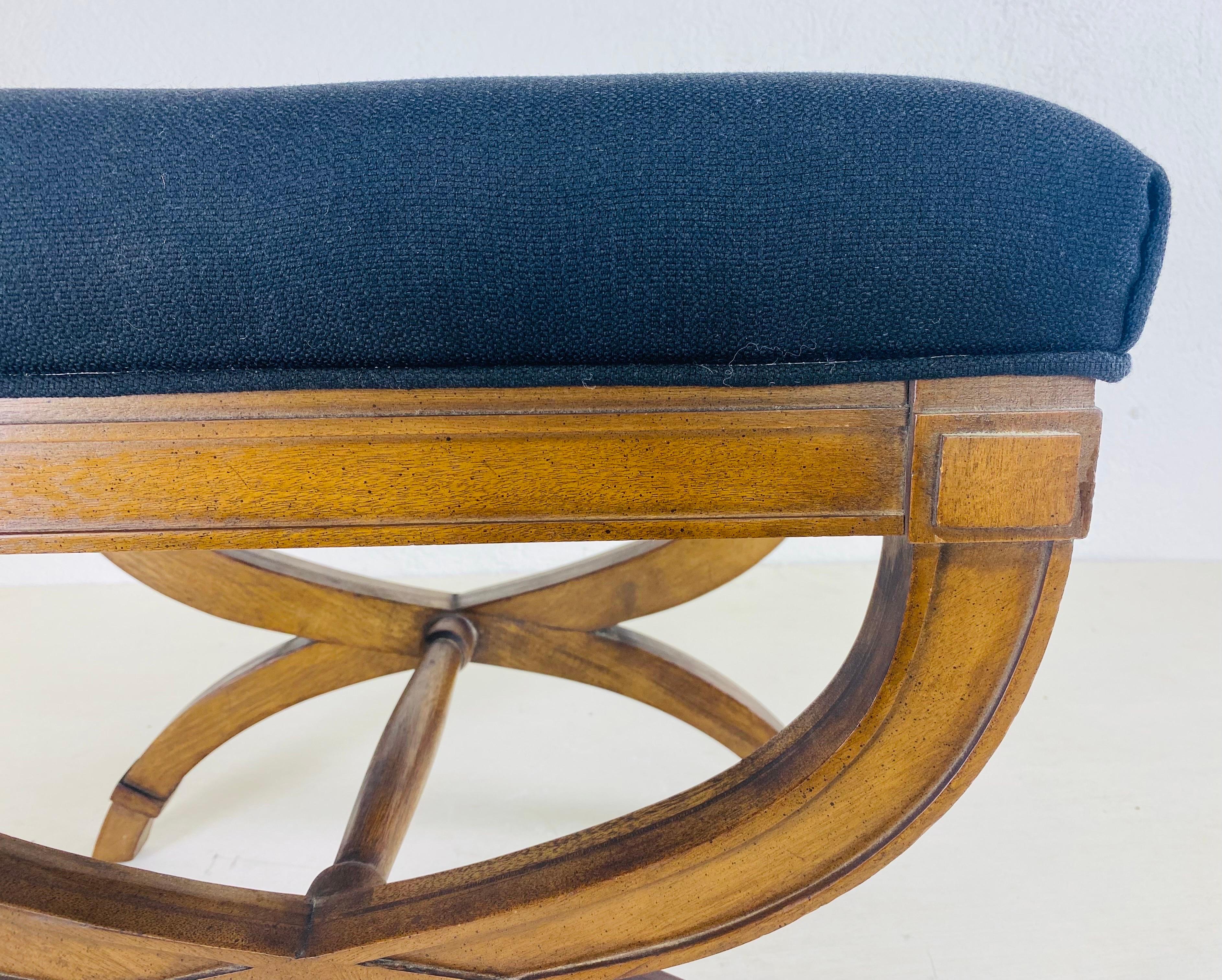 This is a mid century vintage newly upholstered empire inspired bench. This bench has been upholstered in a black cotton with a large button in the center. The bench has a dark walnut finished the surface.