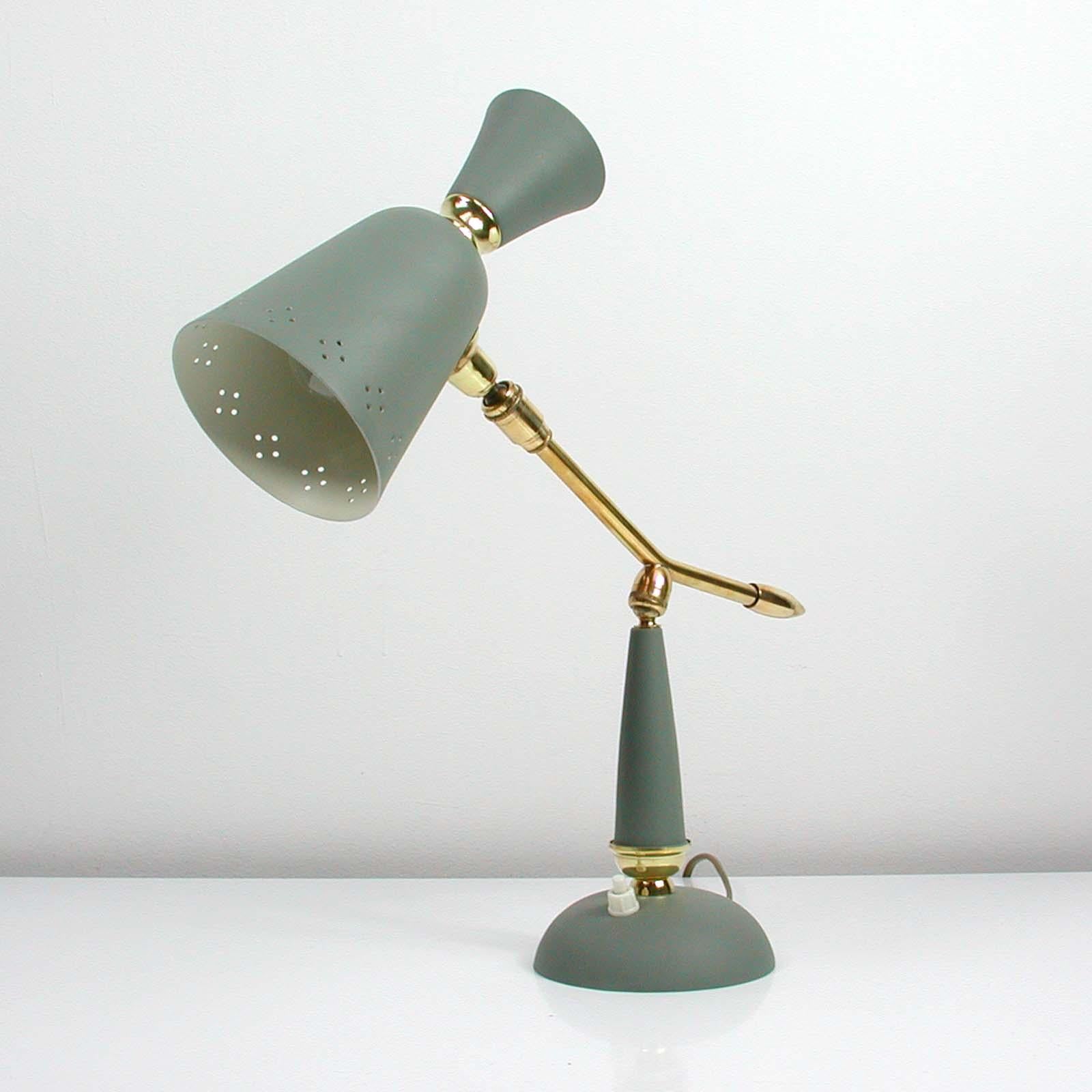 Cette lampe de table vintage du milieu du siècle a été fabriquée en France dans les années 1950. Elle est fabriquée en métal laqué gris et dispose d'un bras de lampe réglable en laiton et d'un abat-jour réglable.

La lampe a une douille E27. Il a