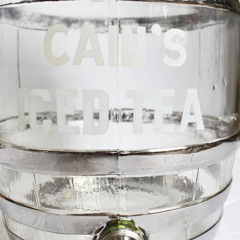 Beautiful glass round iced tea dispenser. A great piece for holding pre-mixed drinks or iced tea for parties or just for storing in your fridge. Made of glass, with a plastic top, and metal spout, the Cain's Ice Tea logo in white is displayed on the