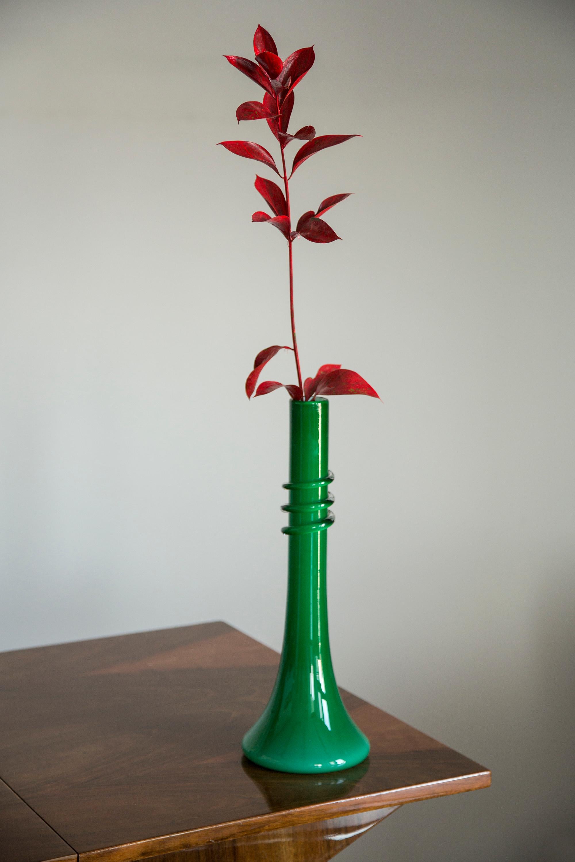 Vase, die nach traditioneller metallurgischer Technik von Hand geformt wurde. Es war aus farbigem Glas in einem Grünton gefertigt. Die Oberfläche des Objekts mit vertikalen Rillen, die im mittleren Teil die Richtung ändern, ineinander übergehen und