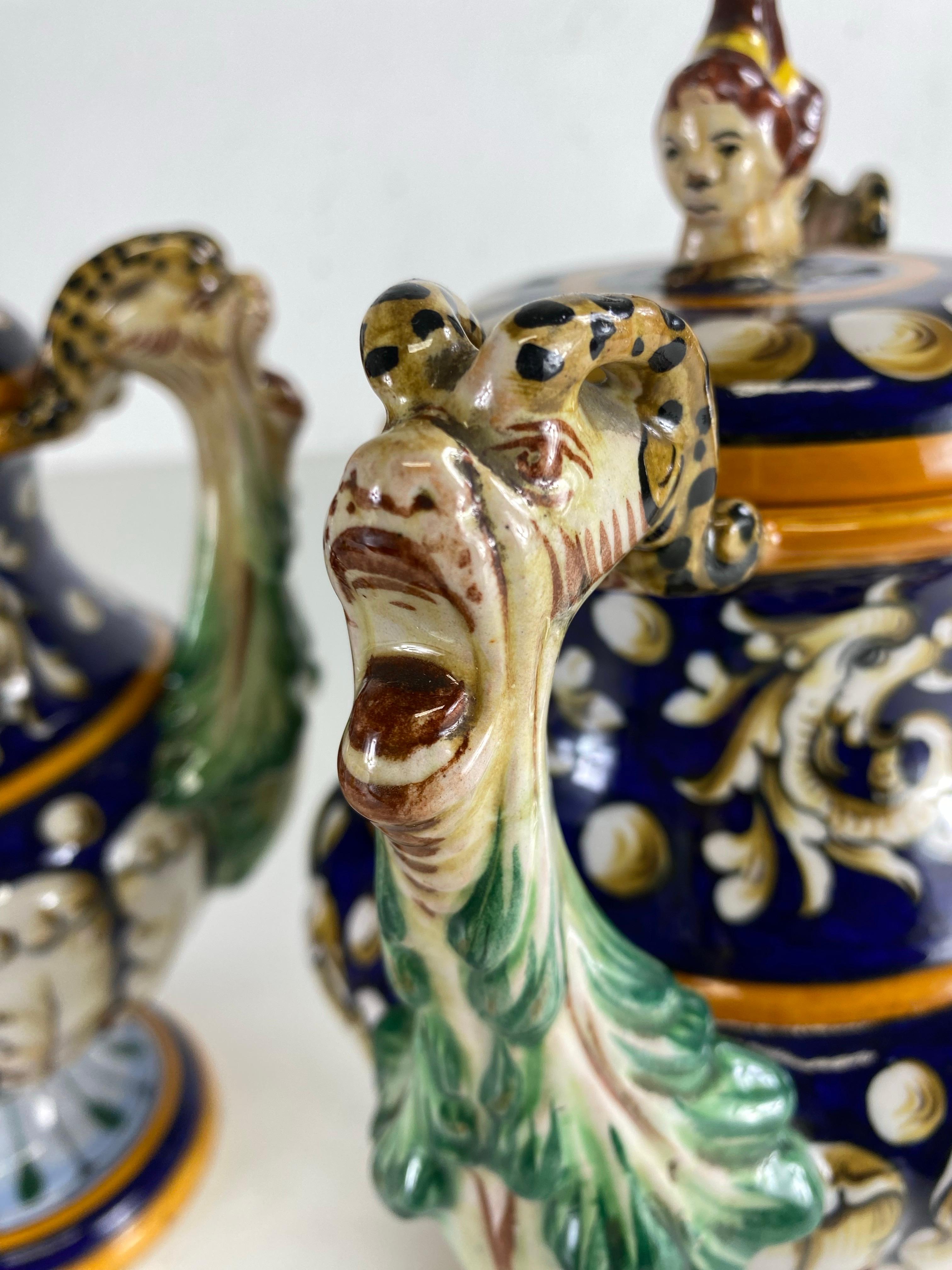Si tratta di una coppia di urne in ceramica italiane dipinte a mano della metà del secolo scorso con coperchio. Questa coppia di urne è caratterizzata da bellissimi manici scolpiti a mano su entrambi i lati con 
 foglie scolpite e sculture di figure