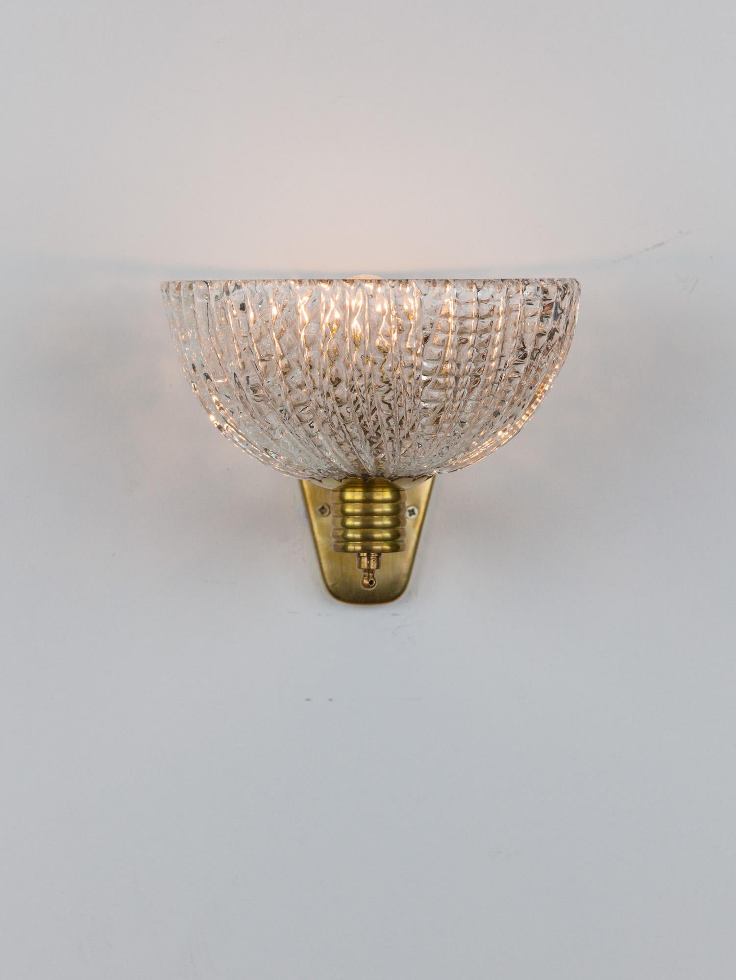 Lovely Italian Barovier wall light with a hemisphere Murano glass shade and wavy arm brass fixture. Impressive in its beauty and form, the textural moulded glass emits a soft ambient light. Made in Italy in the 1940s.

Great vintage condition with