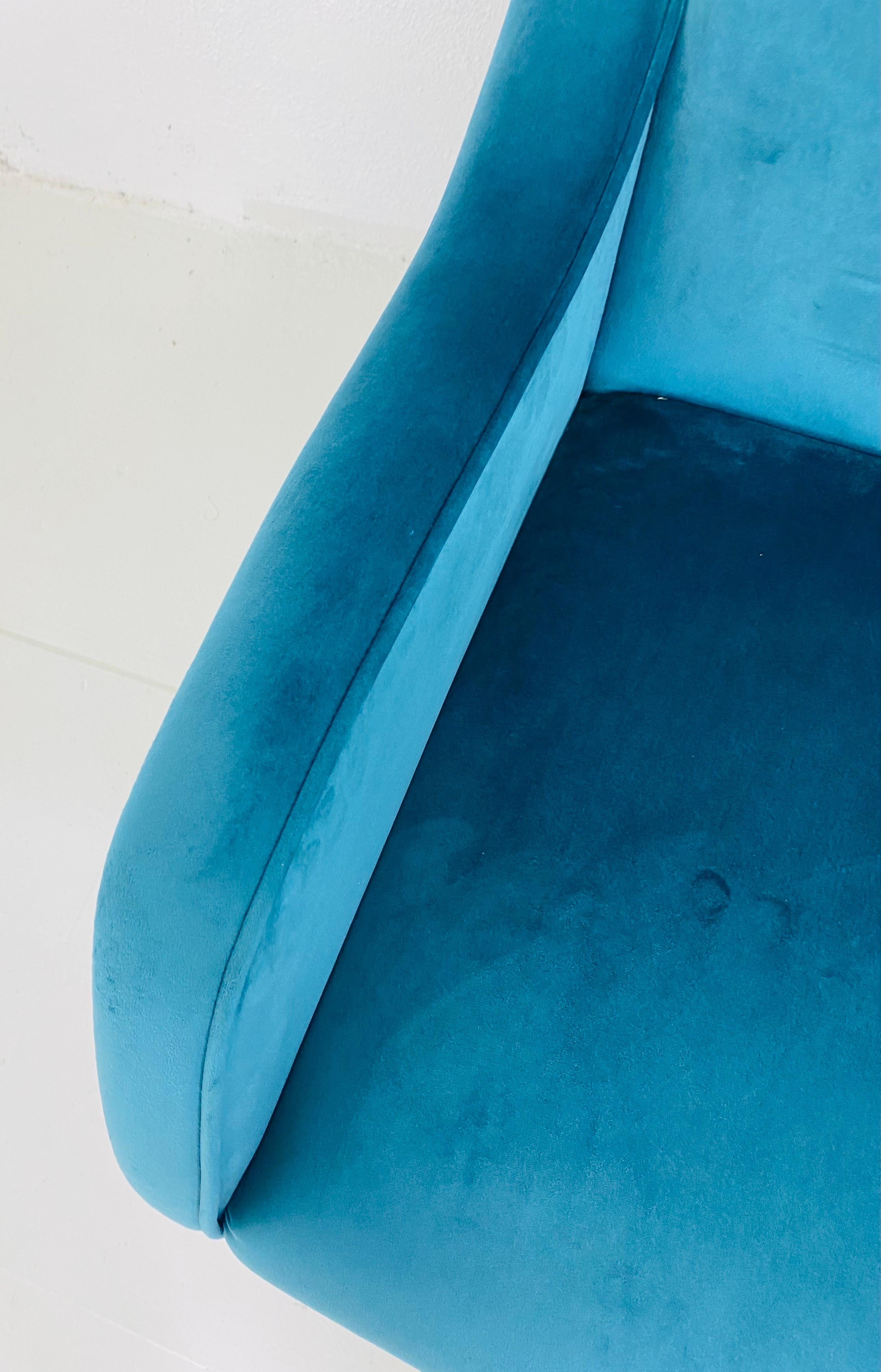 This is a mid-century modern style Italian plush blue velvet sofa. The sofa is newly upholstered and a blue microfiber velvet and is extremely comfortable with a wide seat and a high back. The sculptural Italian sofa has modern brass legs and is in