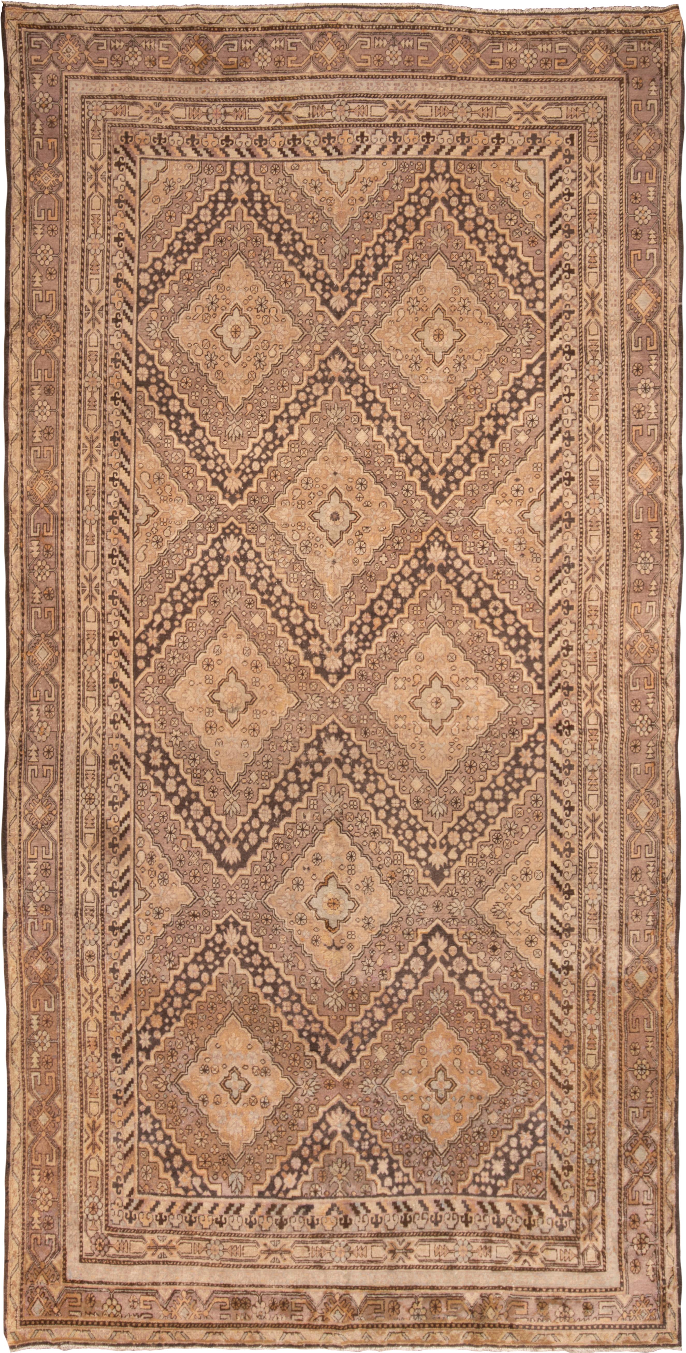 Originating from East Turkestan in 1960, this vintage transitional Khotan rug employs a unique midcentury approach to its geometric field pattern. Hand knotted in high-quality wool, the mesmeric black, beige, and brown medallions continue into other