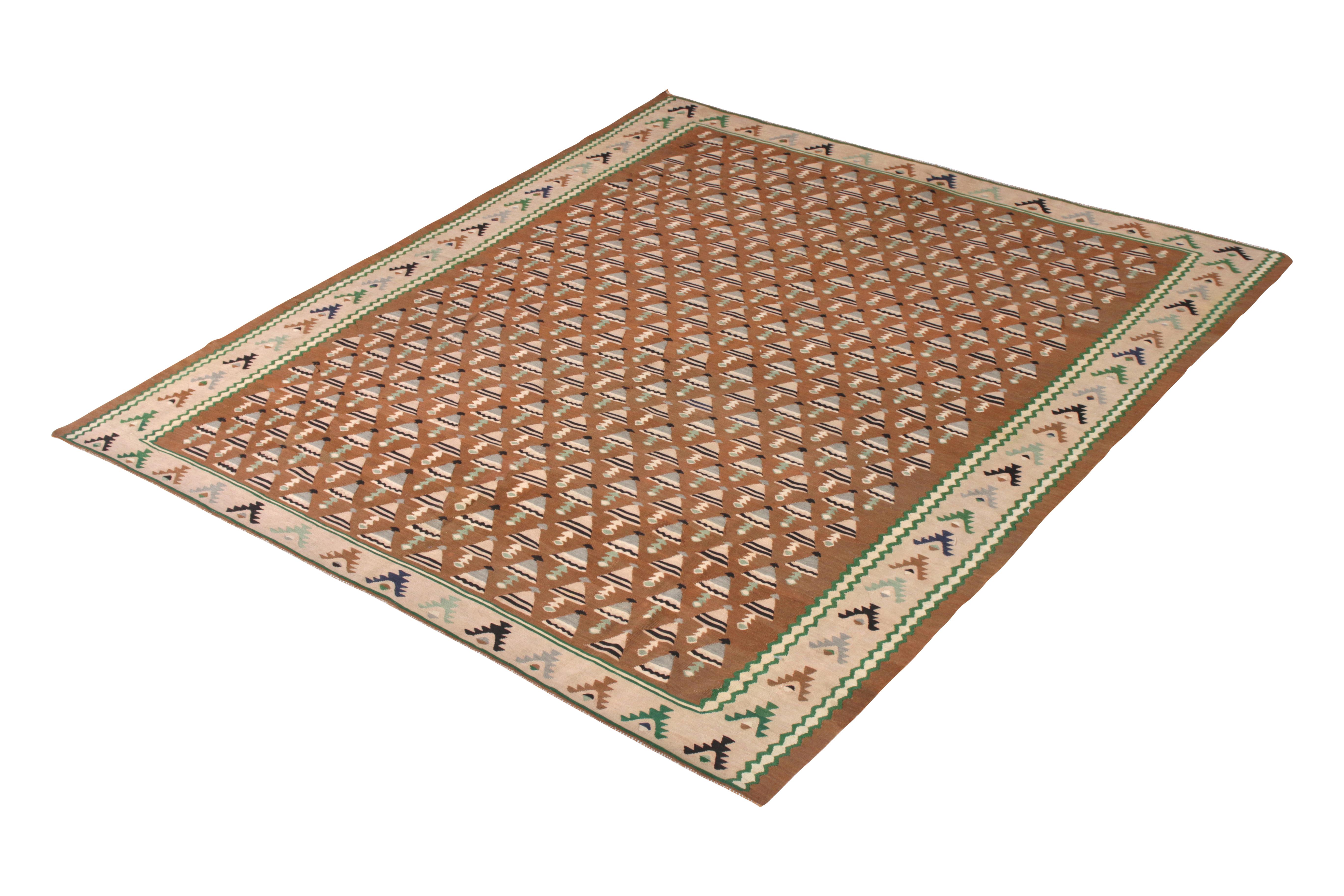 Handwoven in a wool flat weave originating from Turkey circa 1950-1960, this vintage Kilim rug enjoys a mid-century geometric design in a rare colorway, playing a muted beige-pink hue in the border and field geometry with whimsical hues of blue and