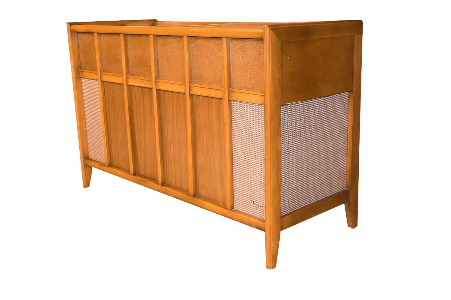 A vintage 1960's Mid-Century Modern stereophonic high-fidelity console by Magnavox. This rare mid century console consists of maple sides, trim and frame, laminate and leather panel inserts. The laminate sliding doors to top provide easy access to