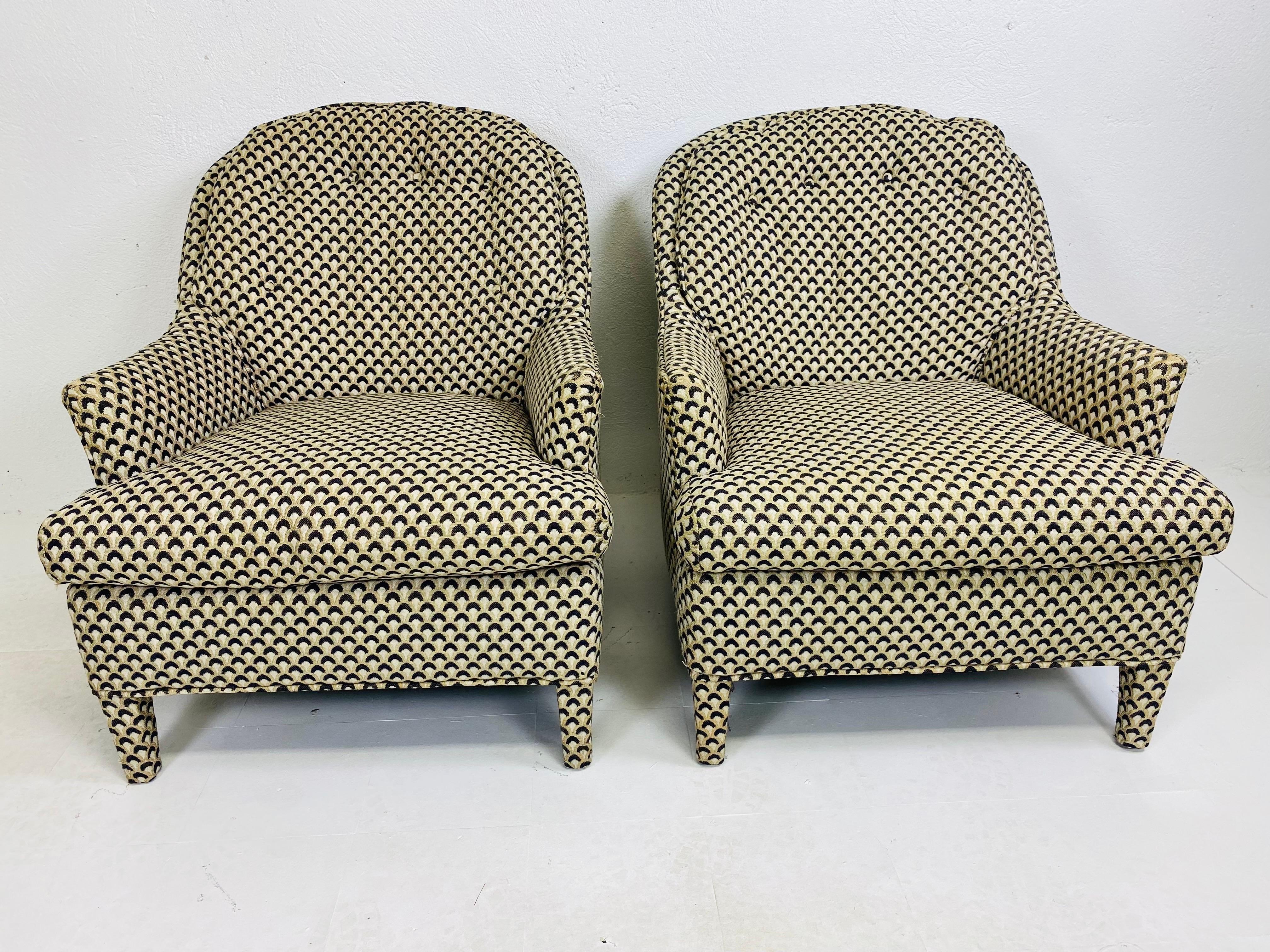This is a pair of mid century modern upholstered club chairs. This pair of club chairs have its original black and white geometric velvet fabric. These club chairs have a persons leg and feature buttons on the back pillows. These chairs are