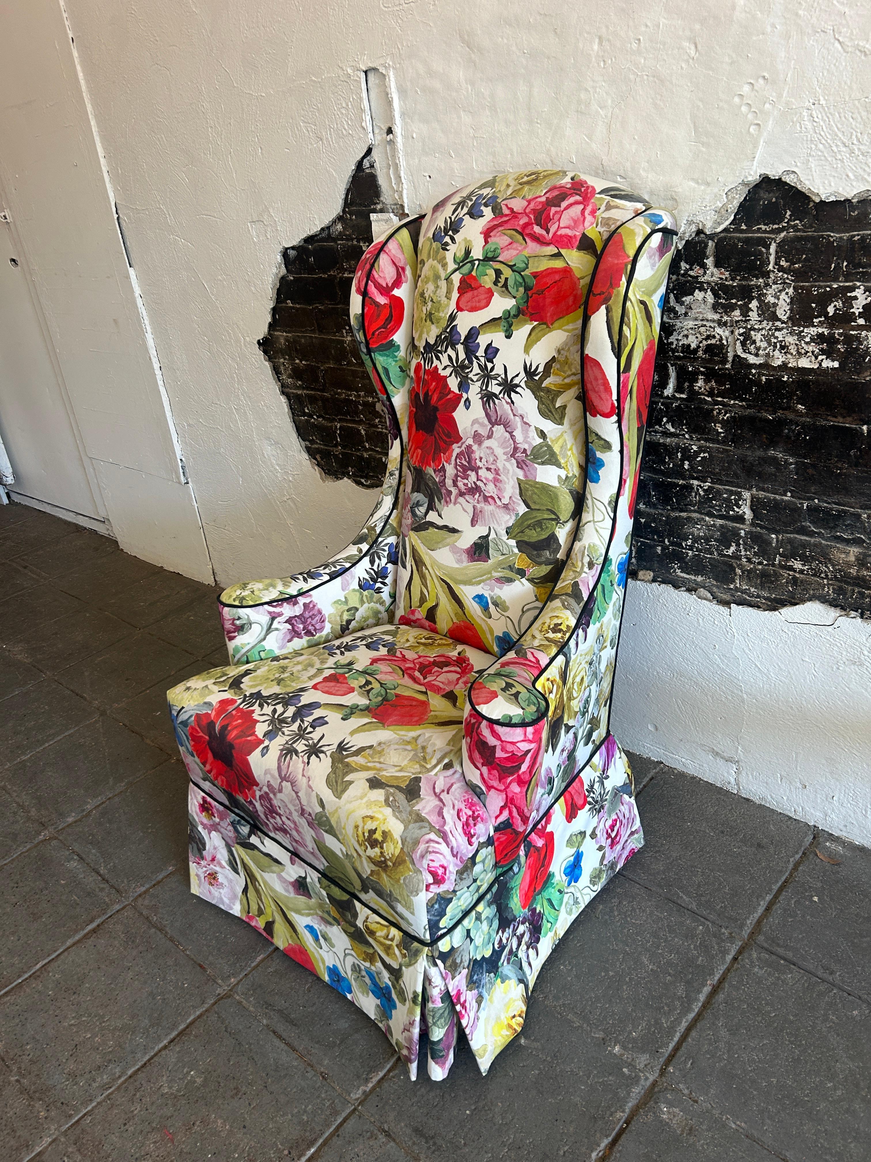 Mid century Vintage narrow tall floral wingback armchair Queen Anne style. Very vibrant watercolor floral upholstery mid century tall narrow wingback chair with lower apron that covers the legs. Very clean chair with black fabric piping. Located in
