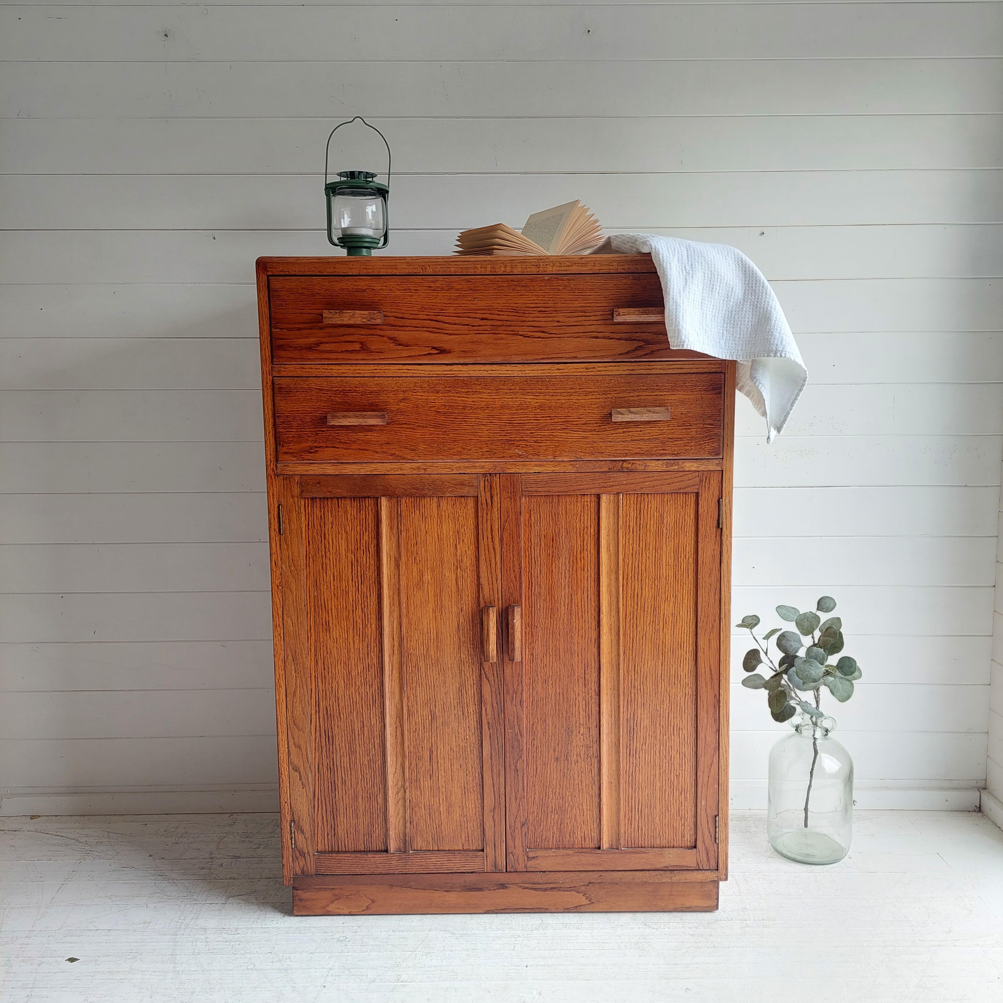 A gorgeous, oak shelved storage cupboard.
A modest piece of oak furniture by the Utility Furniture Advisory Committee. 
Late art Deco early mid century period
1940s
​
The Utility Furniture Advisory Committee set up in 1942, drawing on considerable