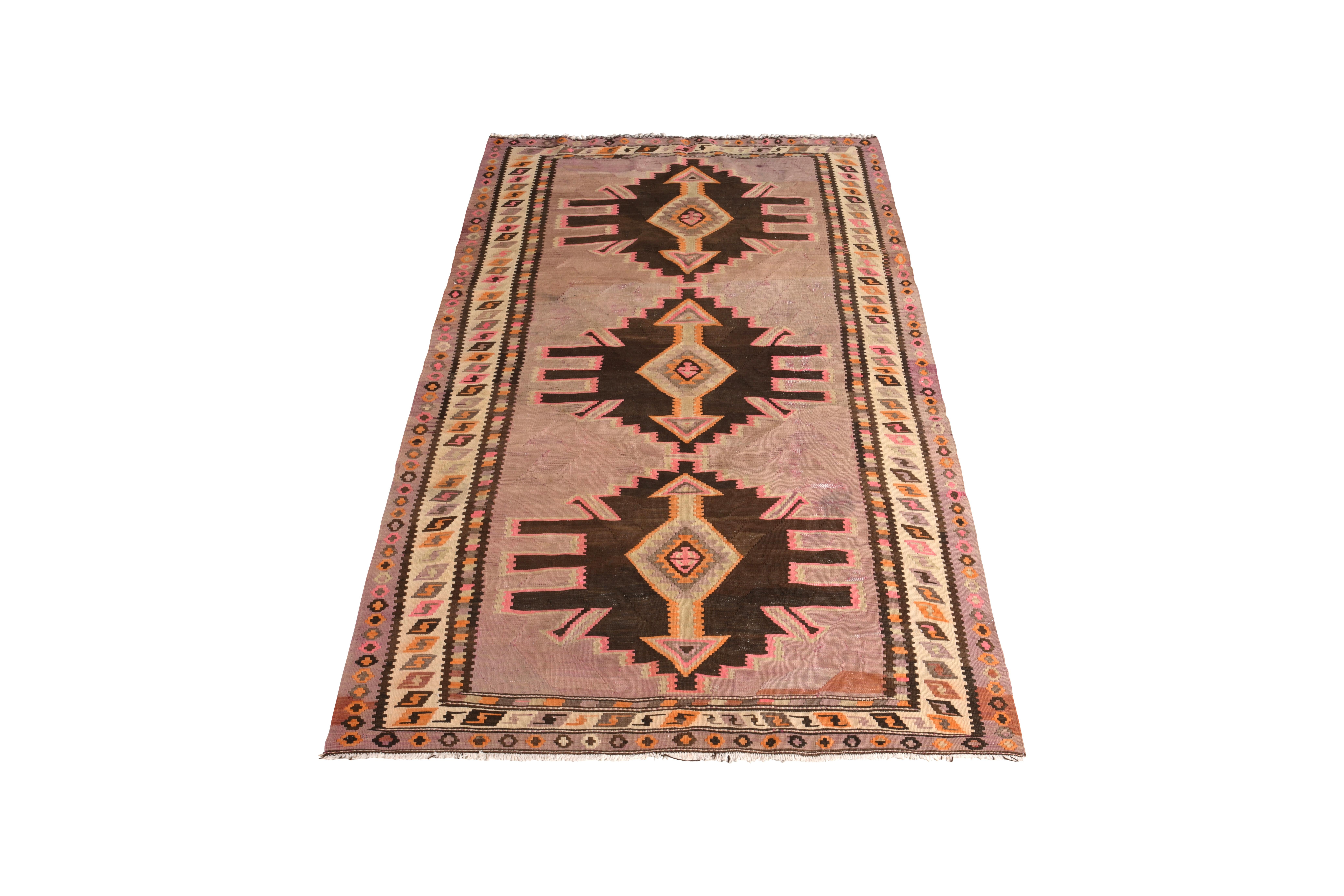 Handmade in flat-woven wool circa 1950-1960, this vintage rug is a midcentury Persian Kilim enjoys both a rare color and arresting sense of depth employed in the juxtaposition of the rich brown with that latter lavender purple colorway. Beyond this
