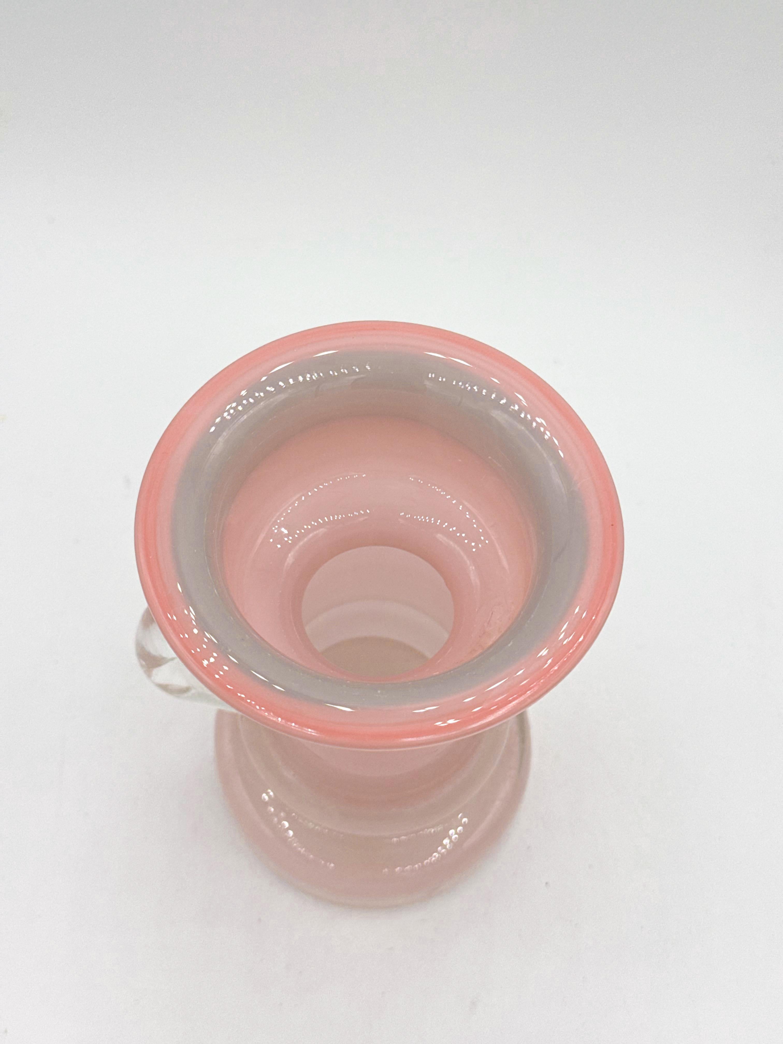 Questo squisito vaso vintage proviene dalla Polonia e risale agli anni '70, un periodo rinomato per la sua innovativa arte vetraria. Alto 5,25 pollici, il vaso presenta una delicata tonalità rosa, caratteristica delle preferenze estetiche